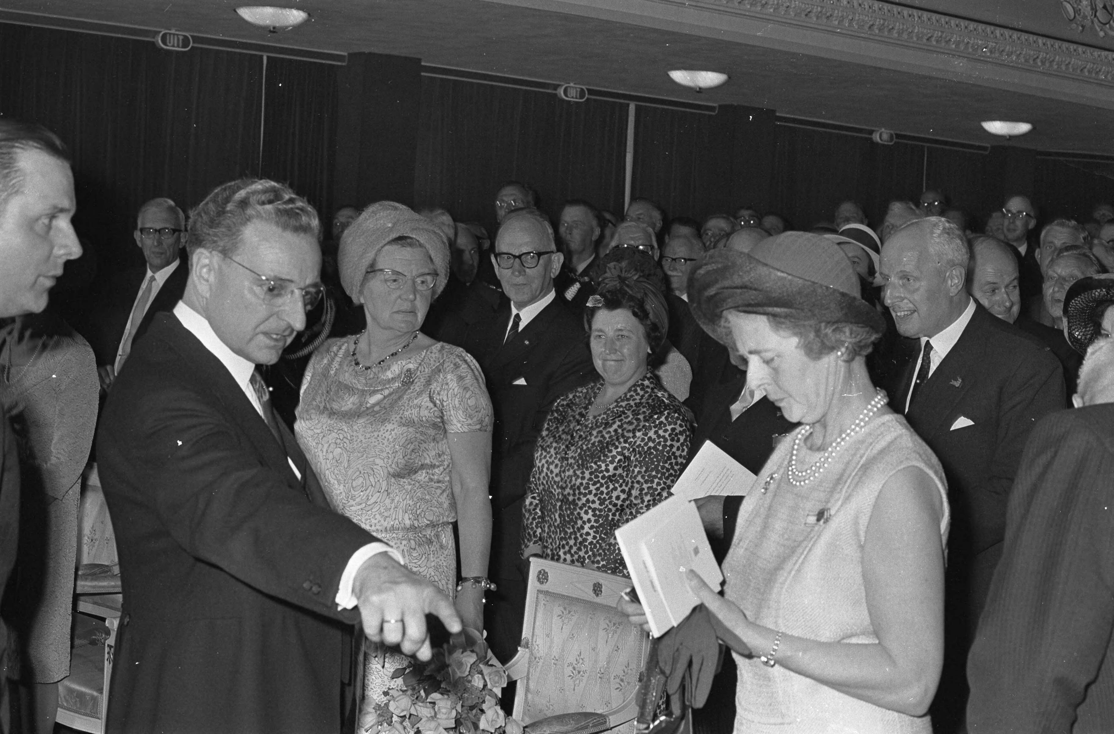 Fotocollectie Anefo — Koningin Juliana bezoekt Maastricht, bij aankomst schouwburg, stoel tekort, Commissaris van de Koningin, de heer Van Rooy vraagt wie daar zit — Foto: Nijs, Jac. de / Anefo. Licentie: Set B: Rechtenvrij / Publiek Domein. Bron: Nationaal Archief. http://hdl.handle.net/10648/ab18bc68-d0b4-102d-bcf8-003048976d84