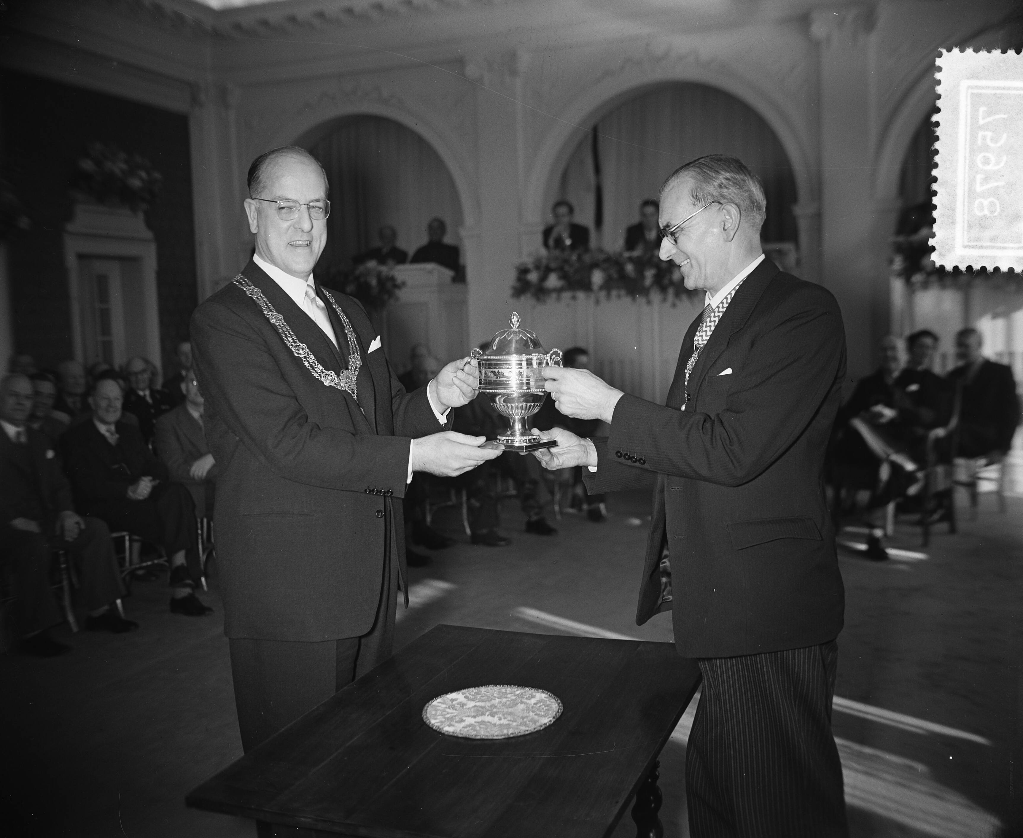 Fotocollectie Anefo — Gemeentebestuur van Londen in Den Haag. Chairman mr. Norman Prichard (rechts) met burgemeester W.F.A. Schokking — Foto: Rossem, Wim van / Anefo. Licentie: Set B: Rechtenvrij / Publiek Domein. Bron: Nationaal Archief. http://hdl.handle.net/10648/a94339cc-d0b4-102d-bcf8-003048976d84