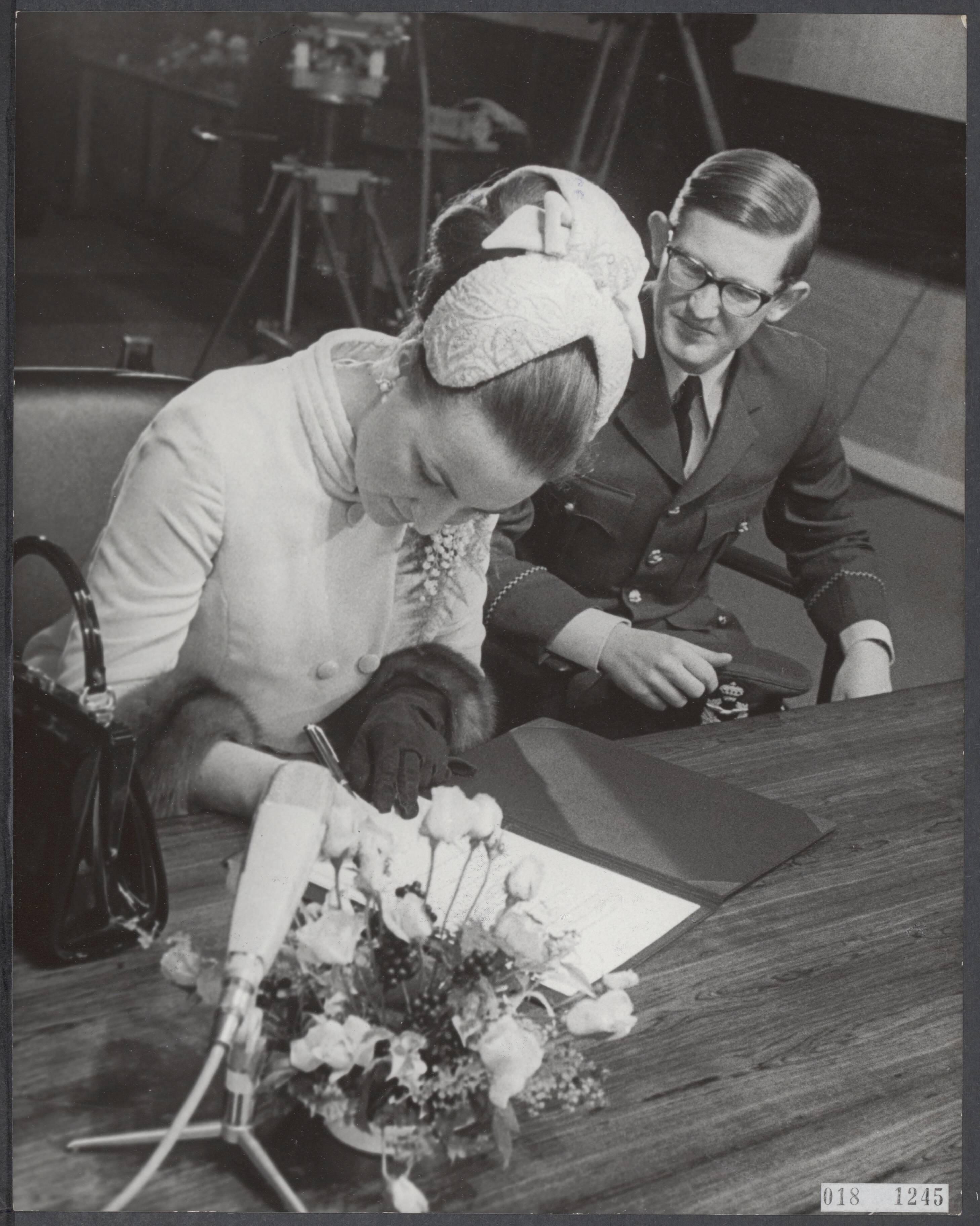 Fotocollectie Elsevier Binnenland — In het Baarnse stadhuis zijn prinses Margriet en mr. Pieter van Vollenhoven ondertrouwd. Prinses Margriet tekent de akte terwijl haar verloofde toekijkt — Foto: Koch, Eric / Anefo. Licentie: Set B: Rechtenvrij / Publiek Domein. Bron: Nationaal Archief. http://hdl.handle.net/10648/adc4b9bc-d0b4-102d-bcf8-003048976d84