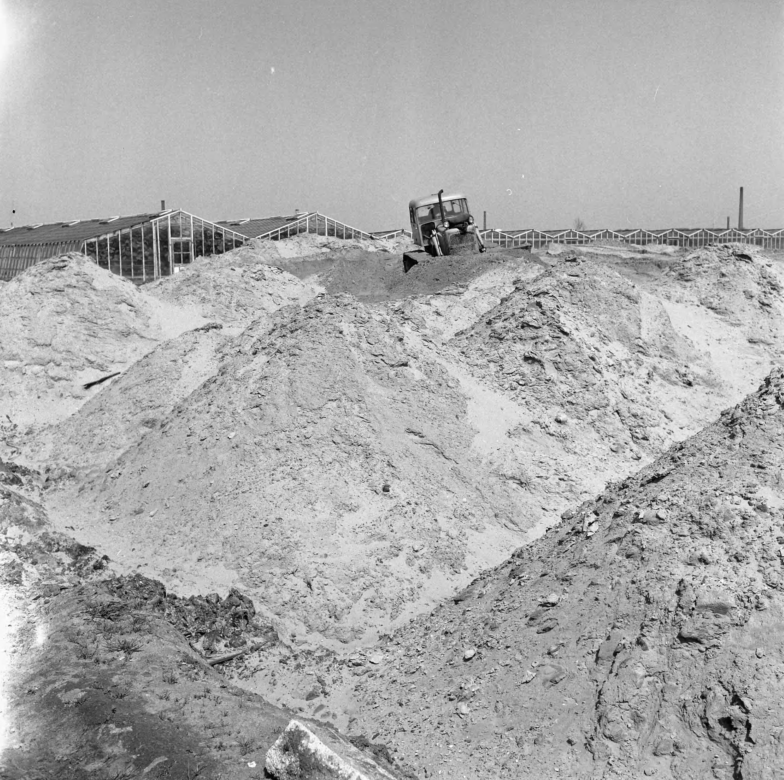 Fotocollectie Nederlandse Heidemaatschappij — Object gemeente 's-Gravenhage. Kerketuinen. Het na te spitten achtergebleven maanlandschap wordt d.m.v een bulldozer geëgaliseerd — Foto: Wüllschleger, [...] / Heidemij. Licentie: Set B: Rechtenvrij / Publiek Domein. Bron: Nationaal Archief. http://hdl.handle.net/10648/ae5e79a8-d0b4-102d-bcf8-003048976d84