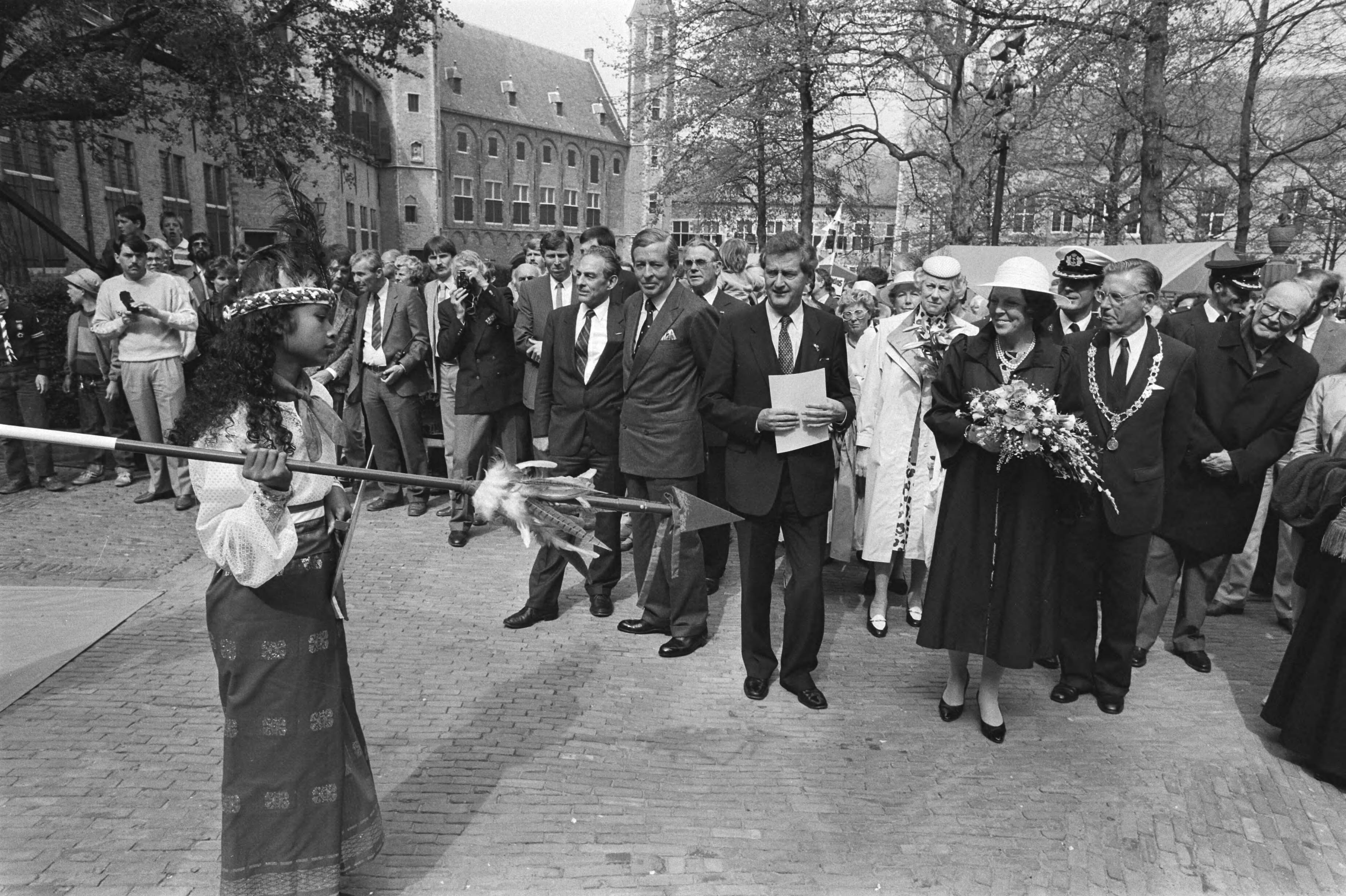 Fotocollectie Anefo — Kon. Beatrix en Prins Claus bij Nat. herdenkingsmanifestatie in Middelburg; Beatrix en Claus kijken naar Moluks meisje van folkloristische groep / — Foto: Bogaerts, Rob / Anefo. Licentie: Set B: Rechtenvrij / Publiek Domein. Bron: Nationaal Archief. http://hdl.handle.net/10648/ad385a62-d0b4-102d-bcf8-003048976d84