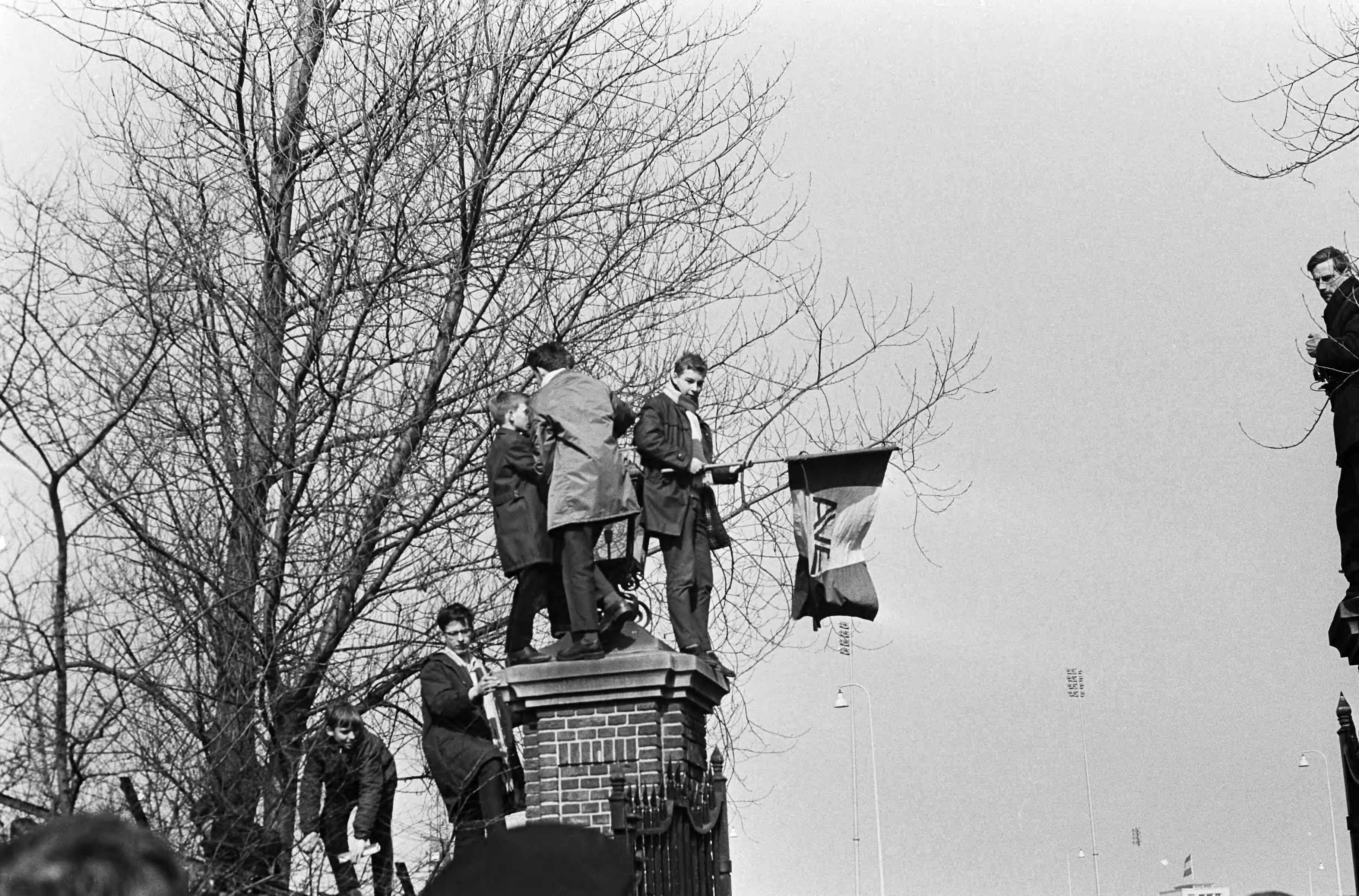 Verloofde paar prinses Margriet en Pieter van Vollenhoven in Den Haag — Verloofde paar in Den Haag , jongeren met vlag op zuil van toegangspoort Catshuis — Foto: Evers, Joost / Anefo. Licentie: Set B: Rechtenvrij / Publiek Domein. Bron: Nationaal Archief. http://hdl.handle.net/10648/aa989bd2-d0b4-102d-bcf8-003048976d84