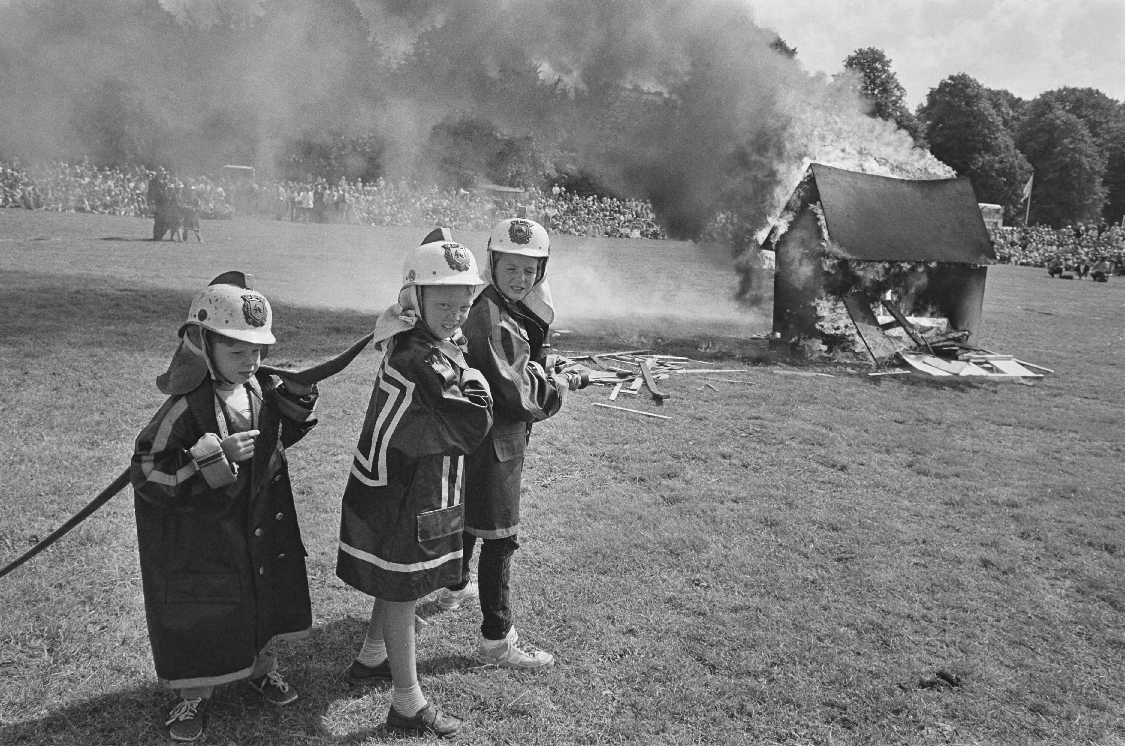 Fotocollectie Anefo — Politie en brandweerfeest op Malieveld in Den Haag; kinderen mogen met brandspuit fik blussen, achtergrond fik — Foto: Bogaerts, Rob / Anefo. Licentie: Set B: Rechtenvrij / Publiek Domein. Bron: Nationaal Archief. http://hdl.handle.net/10648/ad4928b0-d0b4-102d-bcf8-003048976d84