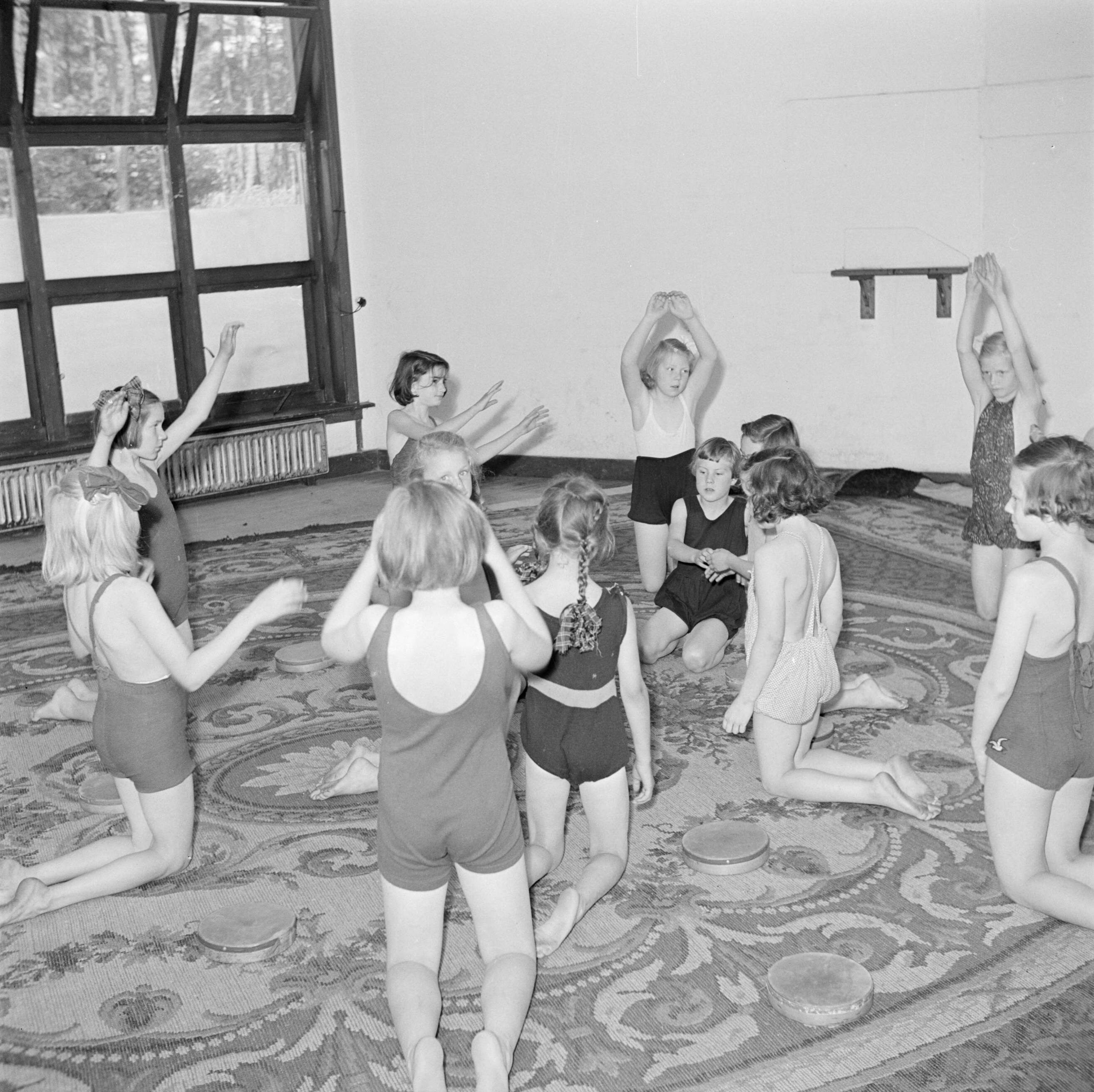 Prinses Beatrix en prinses Irene op de Werkplaats Kindergemeenschap van Kees Boeke te Bilthoven — Prinses Beatrix en andere leerlingen tijdens de gymnastiekles — Foto: Poll, Willem van de. Licentie: Set B: Rechtenvrij / Publiek Domein. Bron: Nationaal Archief. http://hdl.handle.net/10648/aee8156e-d0b4-102d-bcf8-003048976d84