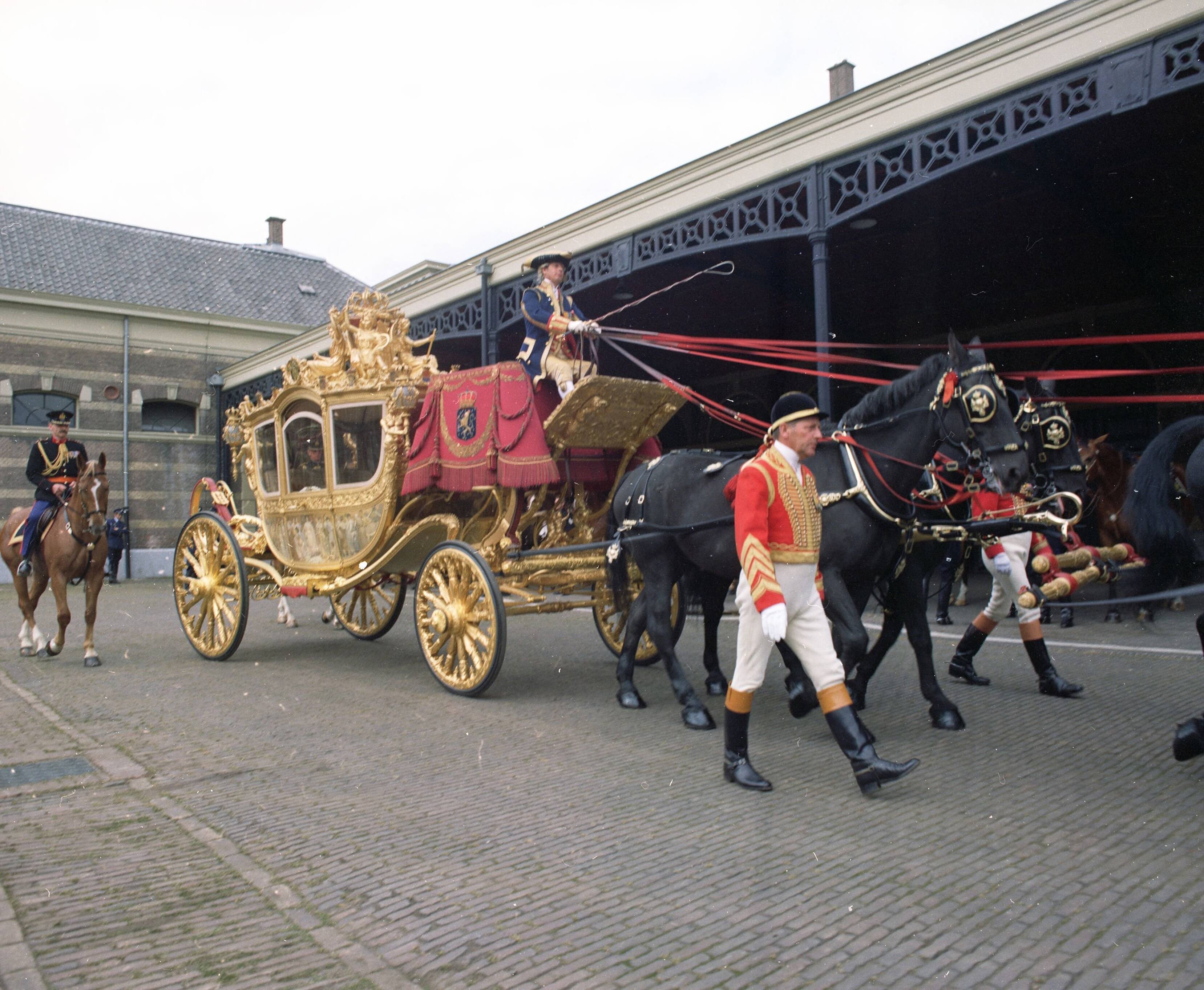Fotocollectie RVD / Koninklijk Huis — Gouden koets met koetsier, stalpersoneel, ruiter te paard en paarden op de binnenplaats van de koninklijke stallen aan de Noordwal in Den Haag — Foto: Mastenbroek, Cees / RVD. Licentie: Set B: Rechtenvrij / Publiek Domein. Bron: Nationaal Archief. http://hdl.handle.net/10648/afb27ade-d0b4-102d-bcf8-003048976d84