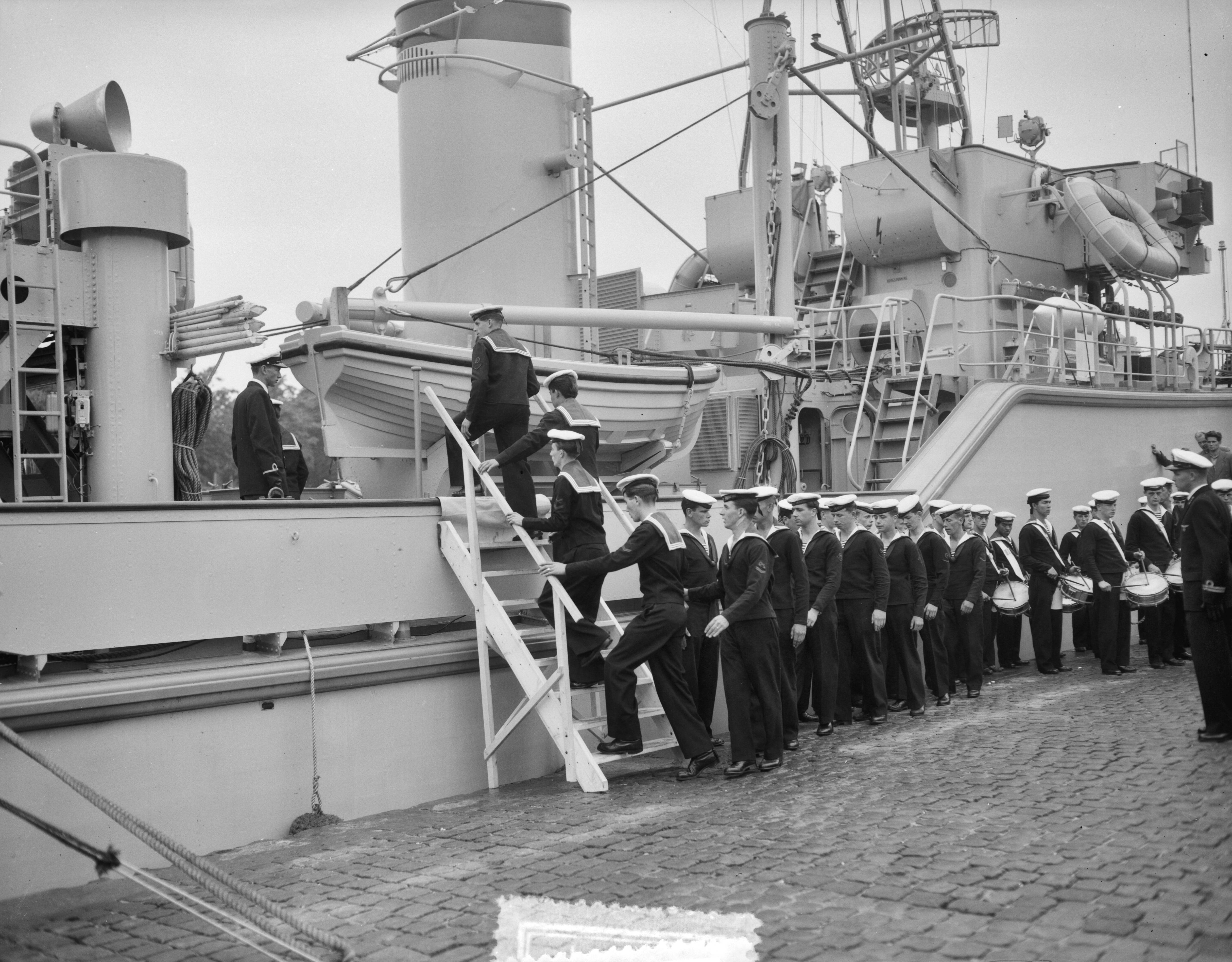 Overdracht en indienststelling van de kustmijnenveger Hr. Ms. "Lochem" in het Verbindingskanaal te Groningen — Overdracht en indienststelling van de kustmijnenveger Hr. Ms. "Lochem" in het Verbindingskanaal te Groningen. De bemanning gaat aan boord — Foto: Behrens, Herbert F. / Anefo. Licentie: Set B: Rechtenvrij / Publiek Domein. Bron: Nationaal Archief. http://hdl.handle.net/10648/a94baf3a-d0b4-102d-bcf8-003048976d84