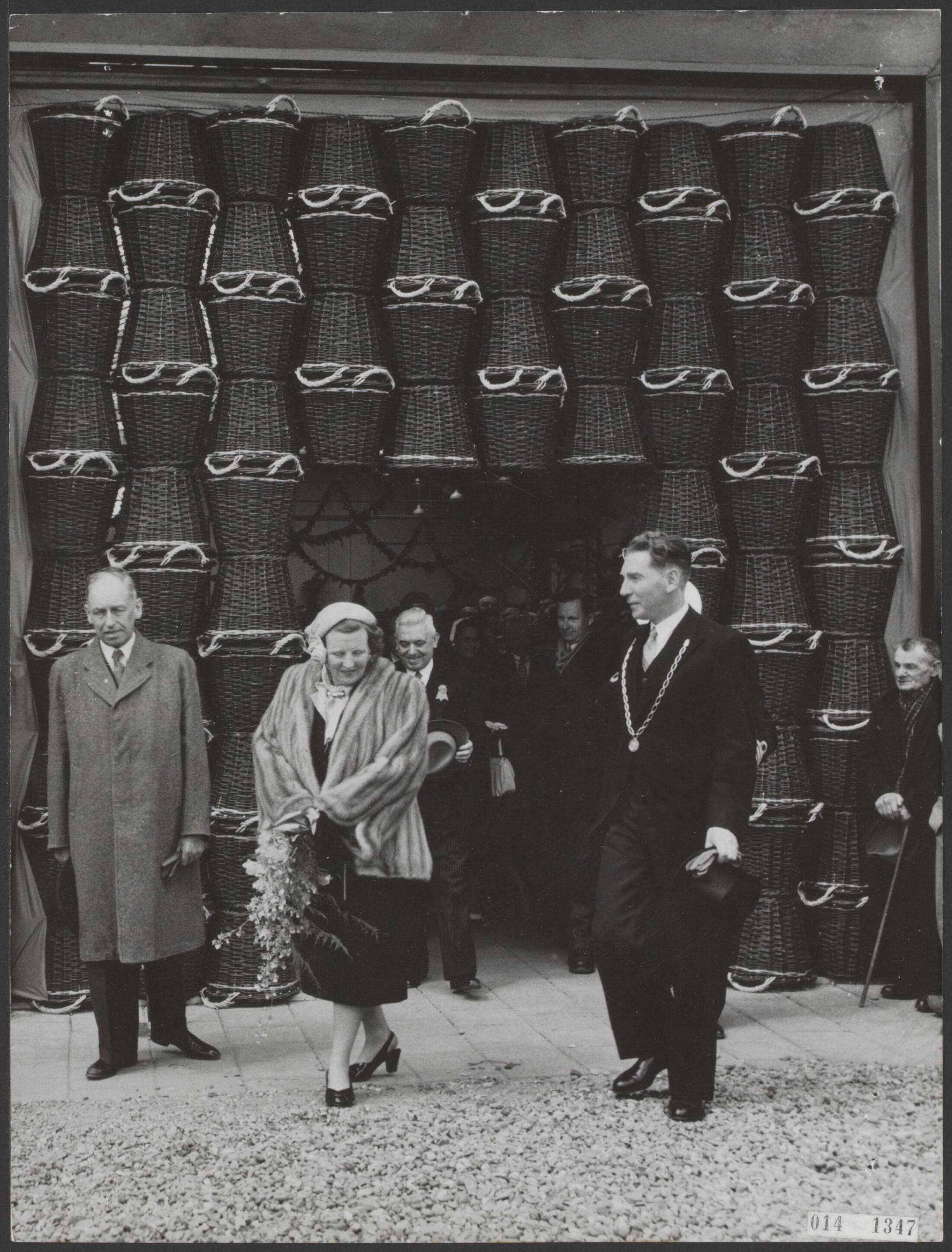 Fotocollectie Elsevier Binnenland — Bezoek van koningin Juliana aan de Rijnstreek. In Ter Aar werd de nieuwe veilinghal geopend, waarbij zij door een poort naar binnen trad. Links mr. L.A. Kesper, commissaris van de Koningin in Zuid-Holland en rechts Ter Aar's burgemeester B.J. Hogenboom — Foto: Fotograaf Onbekend / Anefo. Licentie: Set B: Rechtenvrij / Publiek Domein. Bron: Nationaal Archief. http://hdl.handle.net/10648/adb37e86-d0b4-102d-bcf8-003048976d84