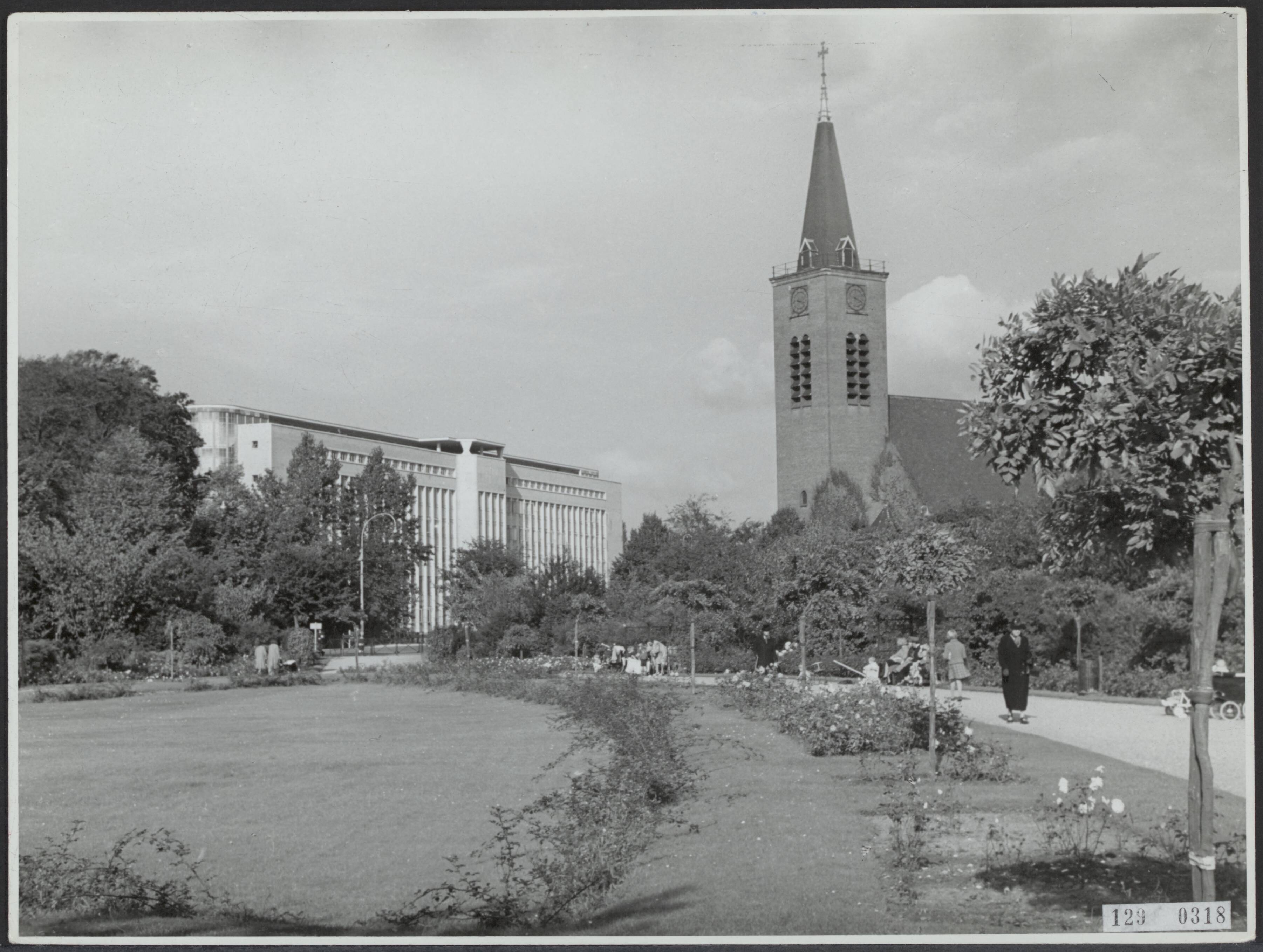 Steden [RVD] — In Den Haag staan naast elkaar het Shellgebouw (BIM-gebouw) van architect J.J.P. Oud en de R.K. Kerk van architect A.J. Kropholler. Op de voorgrond het Rosarium — Foto: Fotodienst Gemeente Den Haag. Licentie: Set B: Rechtenvrij / Publiek Domein. Bron: Nationaal Archief. http://hdl.handle.net/10648/af4621c2-d0b4-102d-bcf8-003048976d84