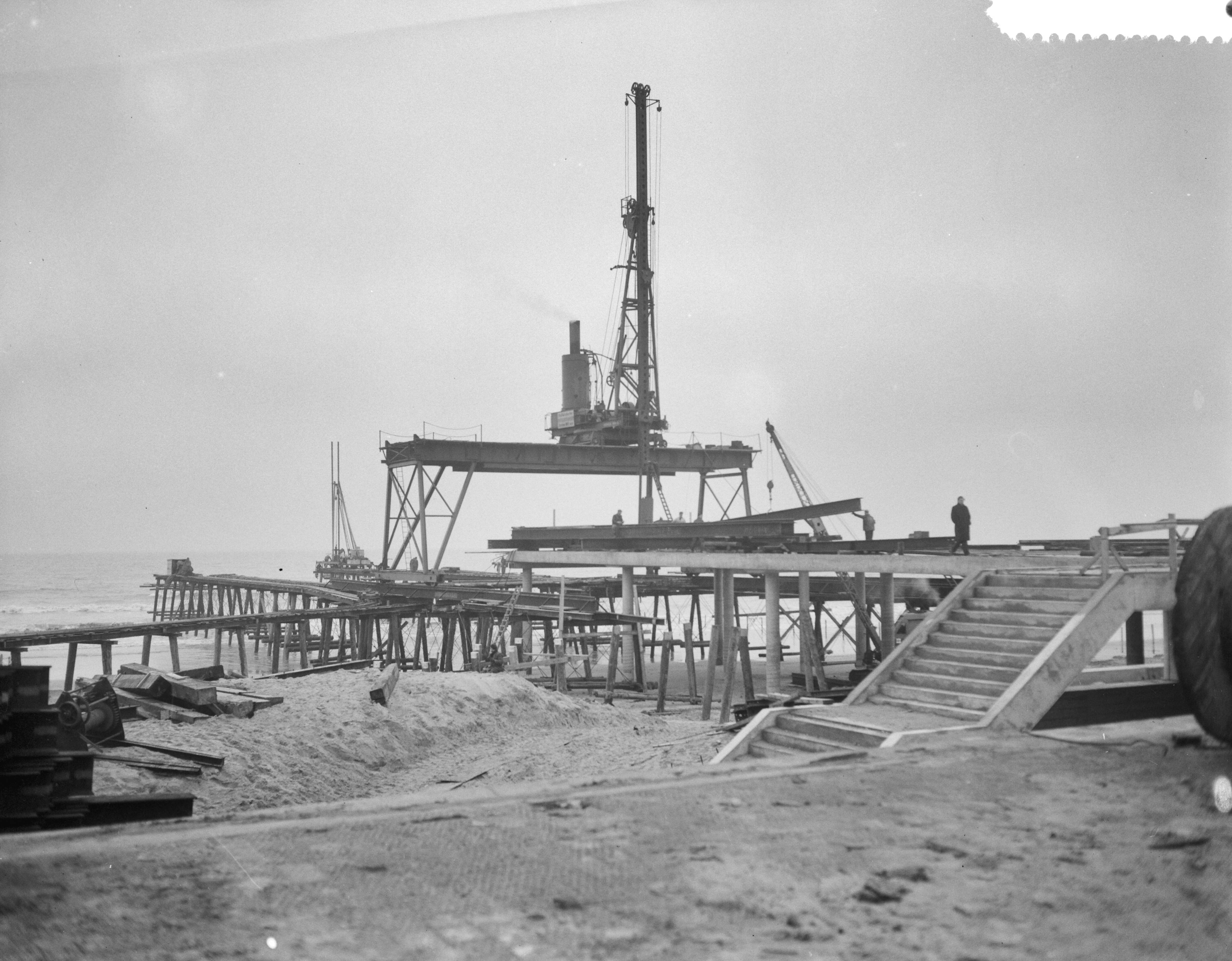 Fotocollectie Anefo — Bouw pier te Scheveningen — Foto: Bilsen, Joop van / Anefo. Licentie: Set B: Rechtenvrij / Publiek Domein. Bron: Nationaal Archief. http://hdl.handle.net/10648/a9a8c328-d0b4-102d-bcf8-003048976d84