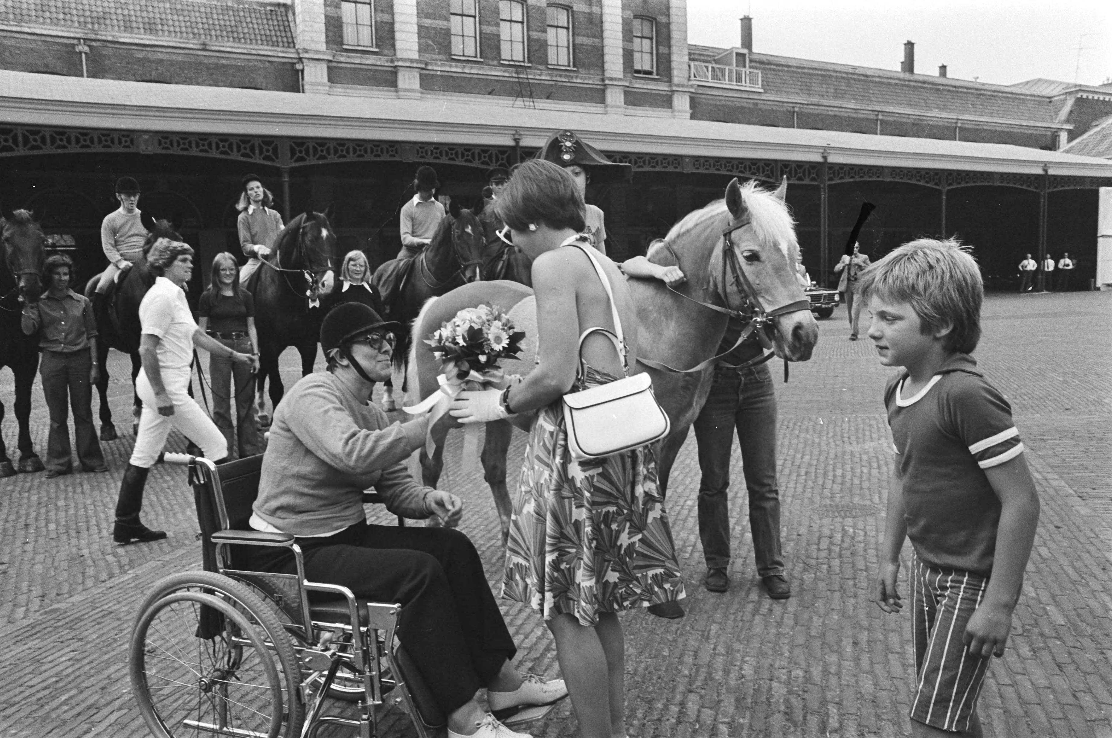 Fotocollectie Anefo — Margriet en Maurits bij demo paardrijden voor gehandicapten in Den Haag , Margriet krijgt bloemen van vrouw in rolstoel, rechts Prins Maurits / — Foto: Mieremet, Rob / Anefo. Licentie: Set B: Rechtenvrij / Publiek Domein. Bron: Nationaal Archief. http://hdl.handle.net/10648/ac85d162-d0b4-102d-bcf8-003048976d84