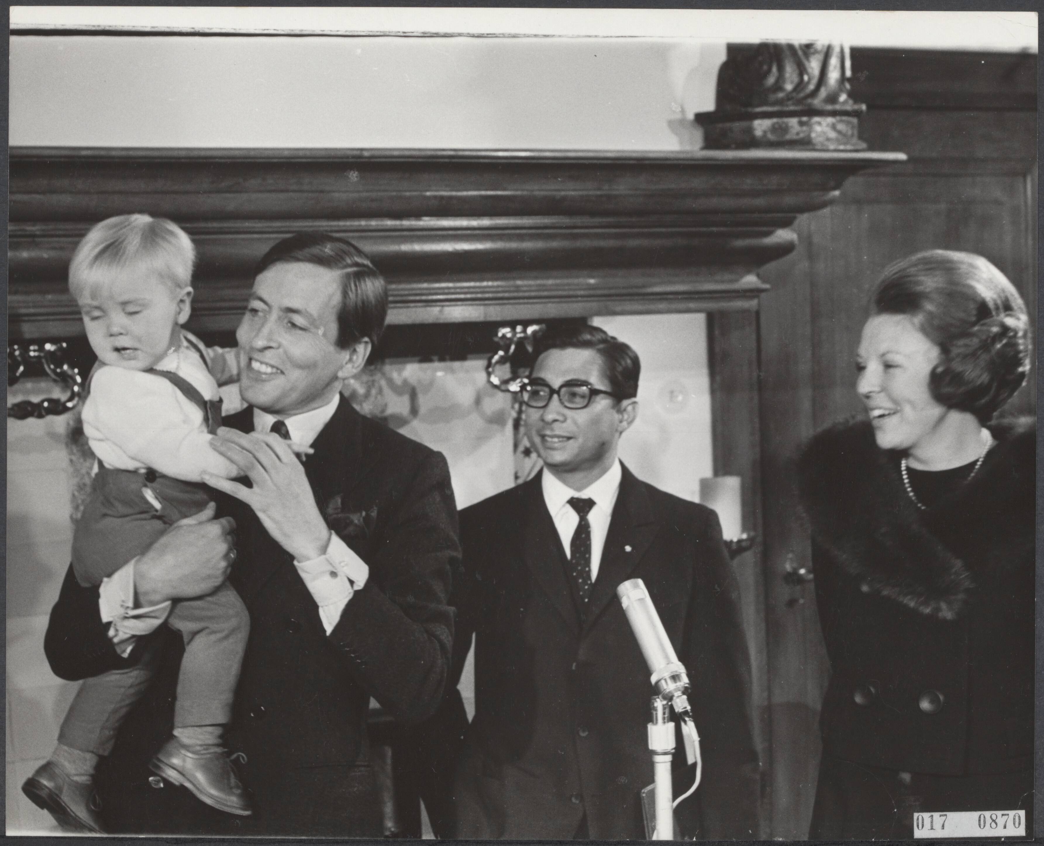 Fotocollectie Elsevier Binnenland — Prinses Beatrix heeft op kasteel Drakensteyn het Surinaamse deel van het huwelijkscadeau overhandigd aan de gevolgmachtigd minister van Suriname mr. Lim A Po. Prins Willem-Alexander op de arm van prins Claus. In het midden mr. Lim a Po — Foto: Kroon, Ron / Anefo. Licentie: Set B: Rechtenvrij / Publiek Domein. Bron: Nationaal Archief. http://hdl.handle.net/10648/adbf43f6-d0b4-102d-bcf8-003048976d84