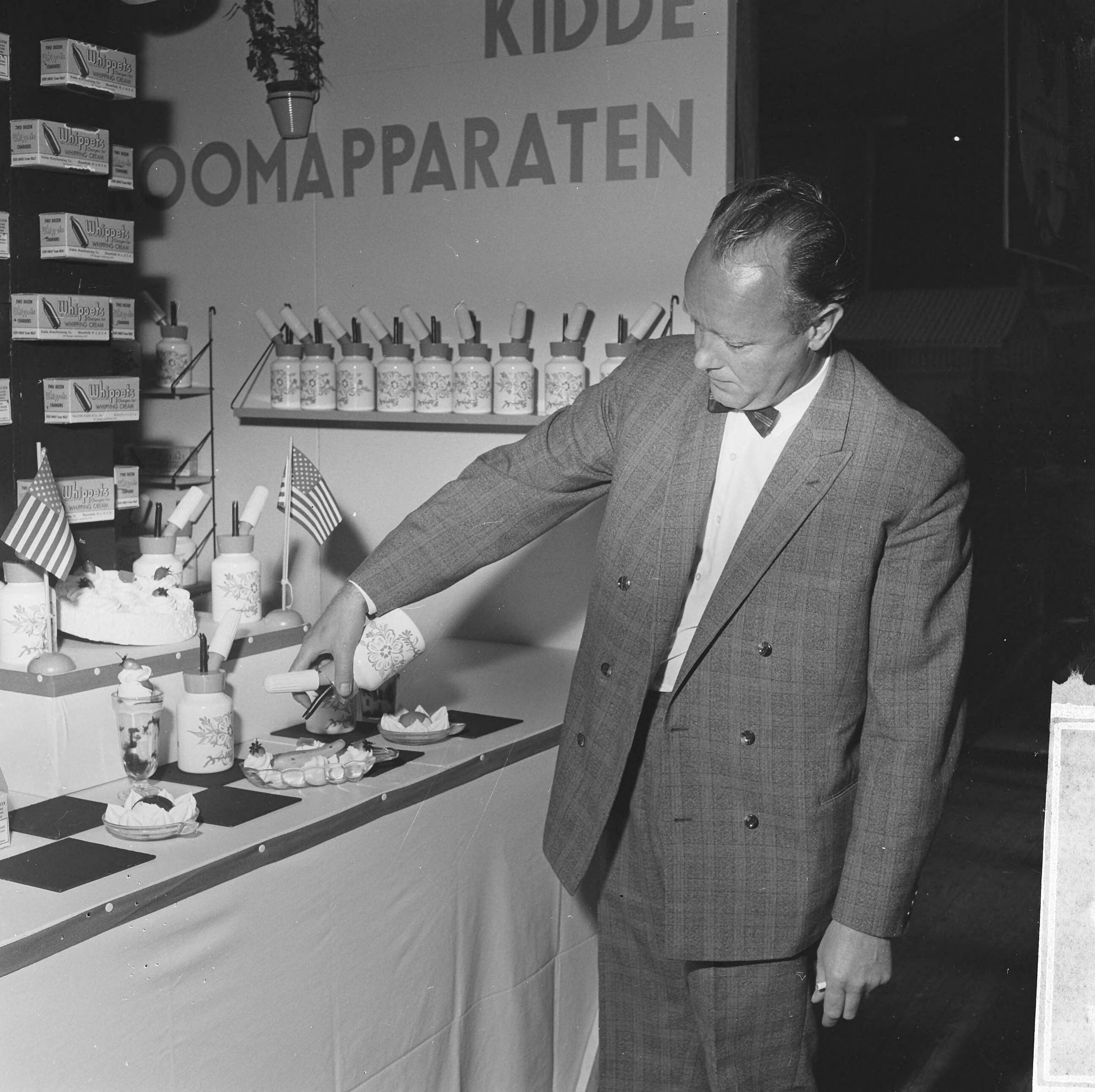 Fotocollectie Anefo — 84ste Damesbeurs in de Houtrusthallen te Den Haag, man demonstreert slagroomspuit — Foto: Voets, Jan / Anefo. Licentie: Set B: Rechtenvrij / Publiek Domein. Bron: Nationaal Archief. http://hdl.handle.net/10648/aac26dcc-d0b4-102d-bcf8-003048976d84