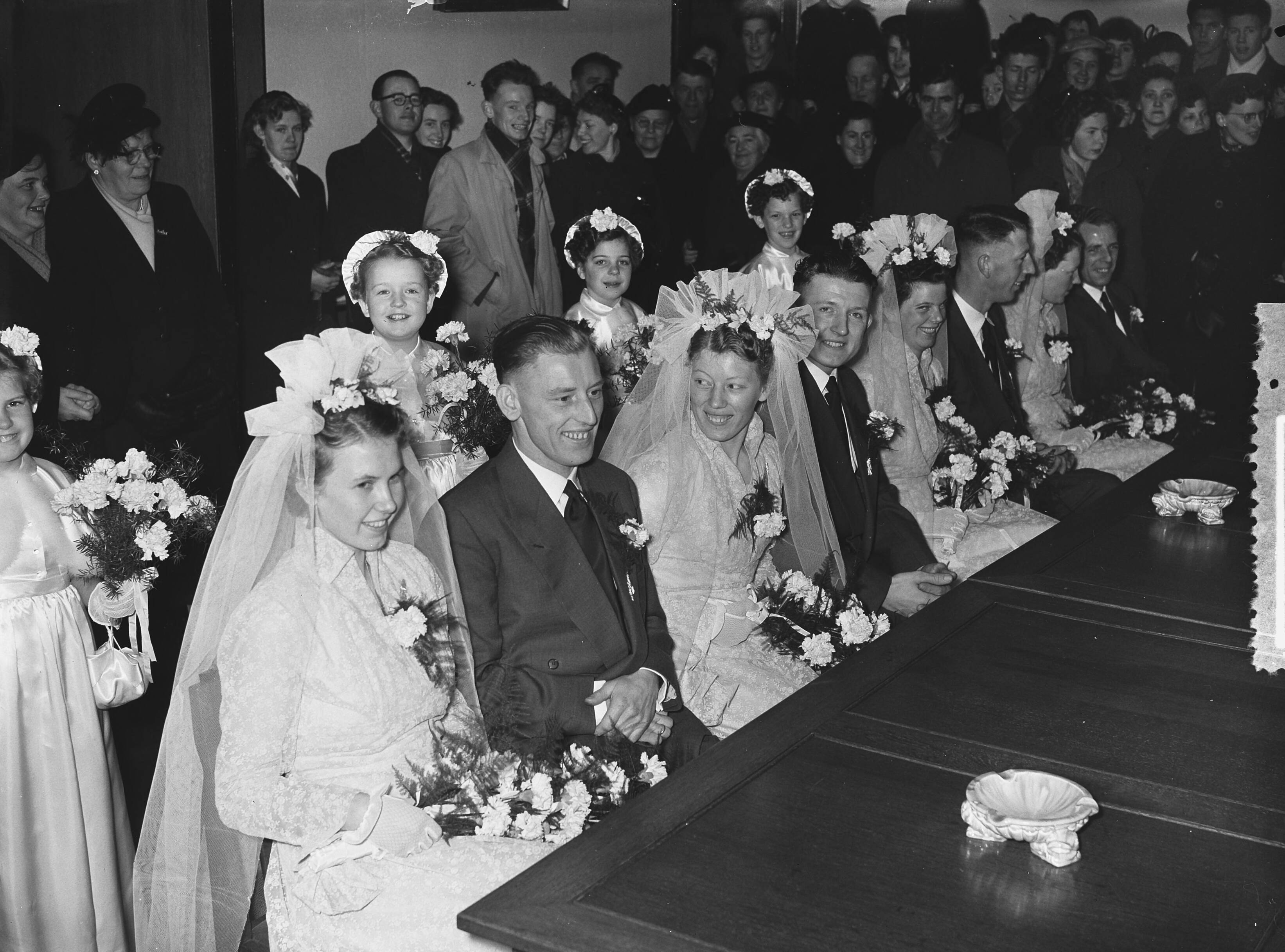 Fotocollectie Anefo — Meervoudige bruiloft. Op het gemeentehuis van Leimuiden trouwden vier telgen uit het gezin Brand (15 kinderen) tegelijkertijd. Vlnr. Het zijn van links naar rechts: Toon Brand (28 jaar, chauffeur) en Catharina Lemmens, Nellie Brand (23 jaar) en Theo Obdam (timmerman), Bram Brand (26 jaar, metselaar) en Bep Könst, en Dora Brand (24 jaar) en Kees Könst (bloemist) — Foto: Pot, Harry / Anefo. Licentie: Set B: Rechtenvrij / Publiek Domein. Bron: Nationaal Archief. http://hdl.handle.net/10648/a930ca76-d0b4-102d-bcf8-003048976d84