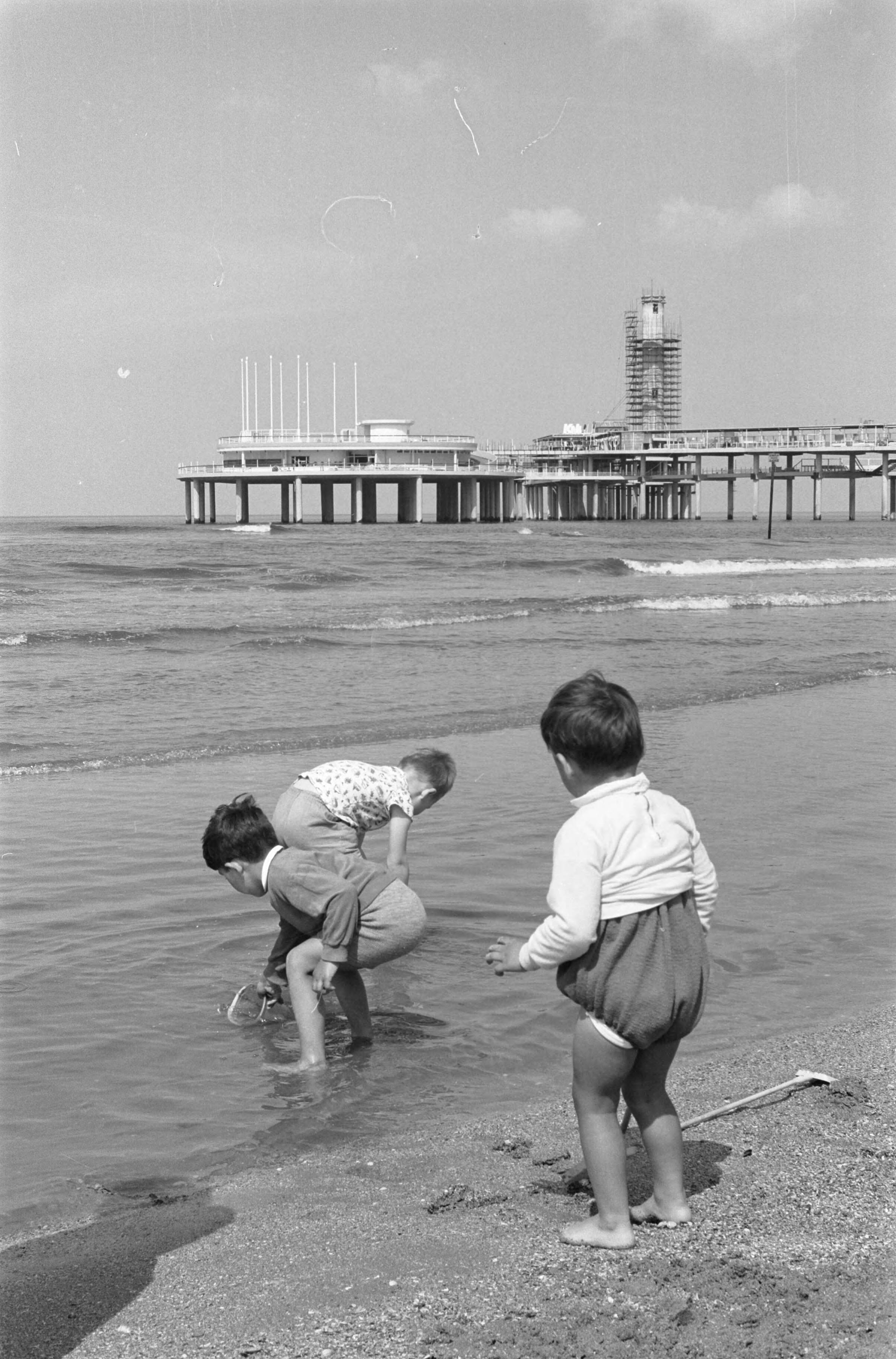 Fotocollectie Anefo — De nieuwe Pier in Scheveningen. Strandbeeld met in de achtergrond de nieuwe pier in aanbouw — Foto: Pot, Harry / Anefo. Licentie: Set B: Rechtenvrij / Publiek Domein. Bron: Nationaal Archief. http://hdl.handle.net/10648/a9d2e1da-d0b4-102d-bcf8-003048976d84
