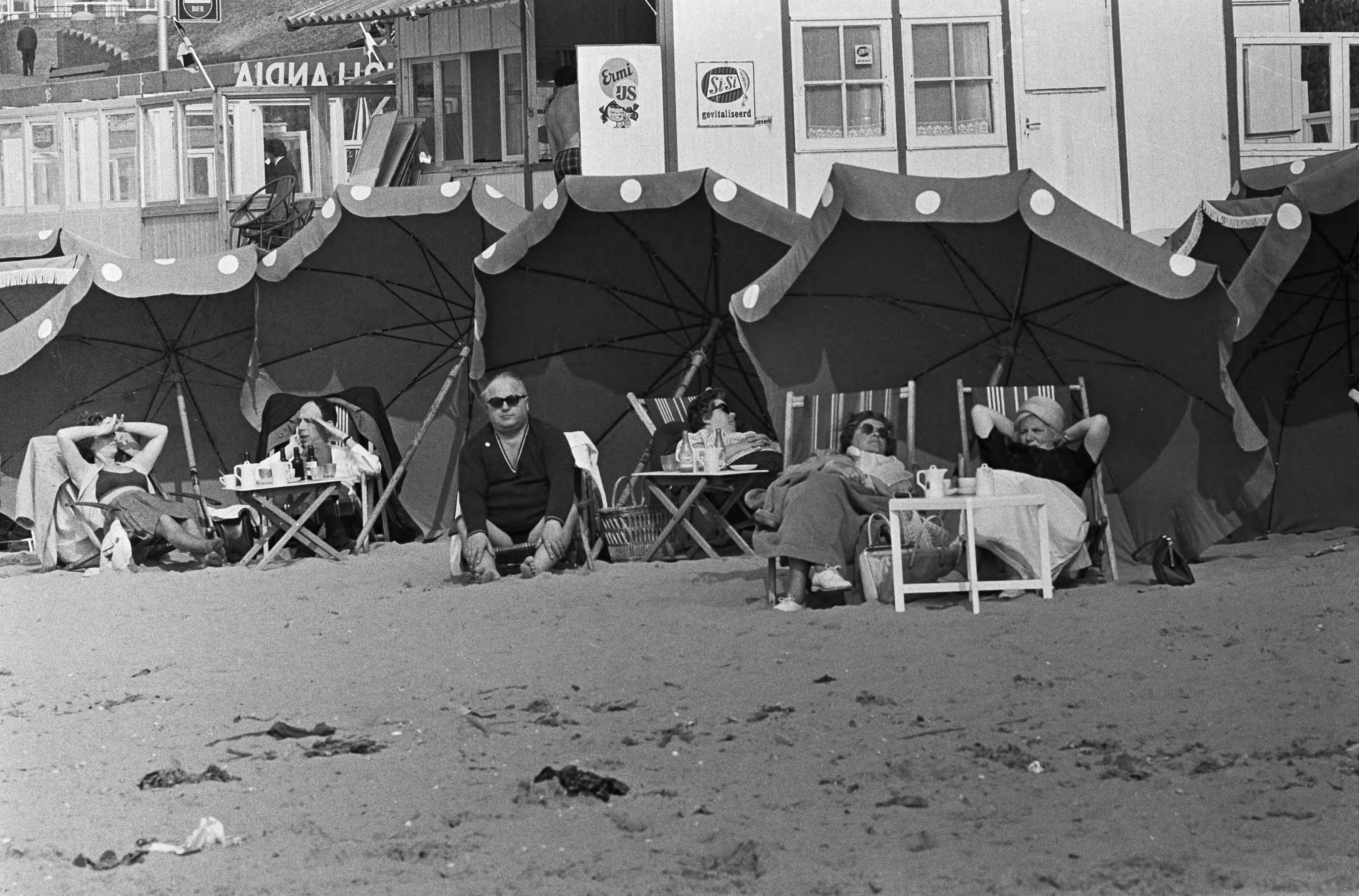 Fotocollectie Anefo — Zonaanbidders onder parasols op het Scheveningse strand — Foto: Steinmeier, Hans / Anefo. Licentie: Set B: Rechtenvrij / Publiek Domein. Bron: Nationaal Archief. http://hdl.handle.net/10648/aaa44504-d0b4-102d-bcf8-003048976d84