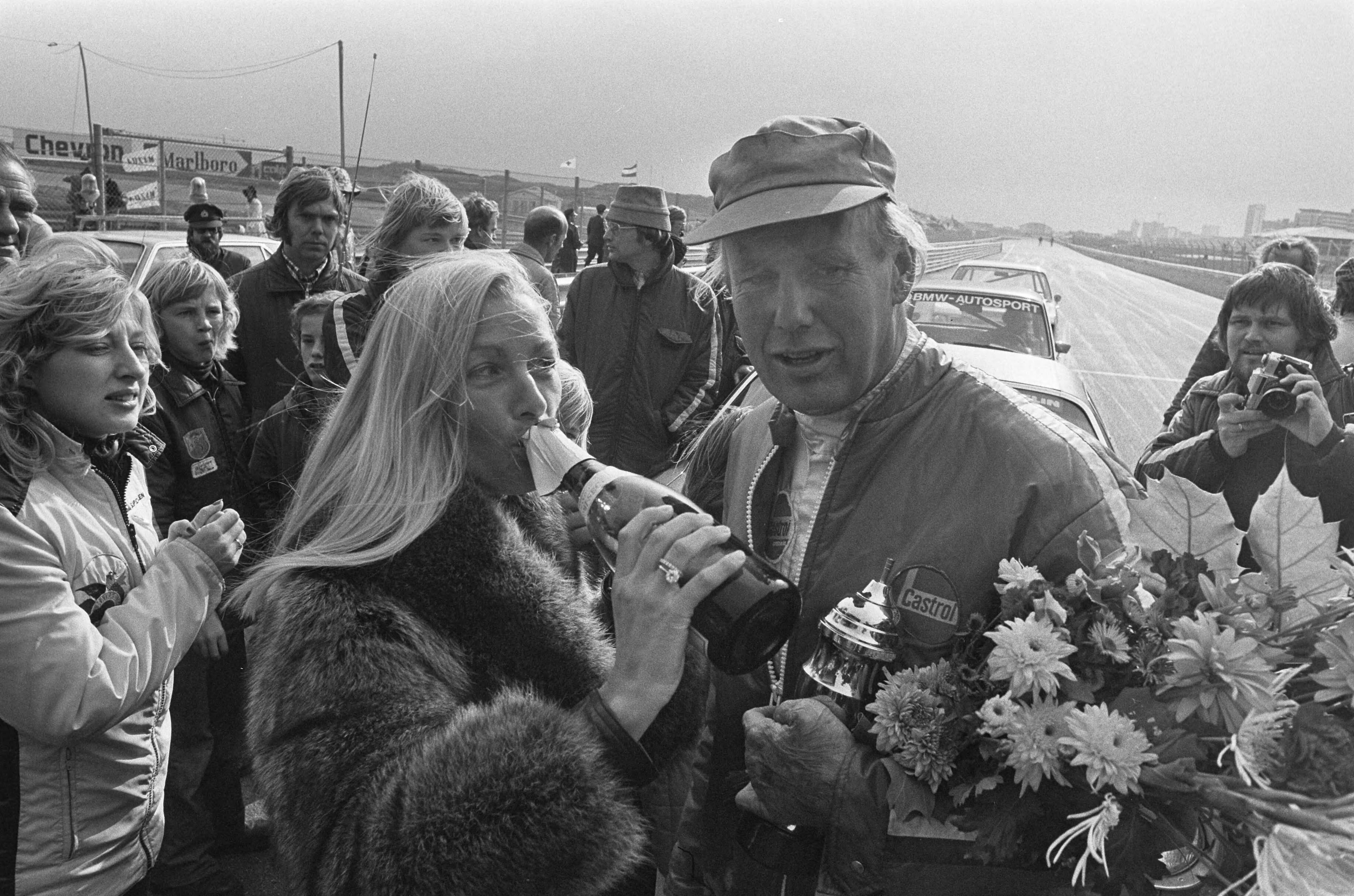 Fotocollectie Anefo — Finaleraces Nederlandse kampioenschappen op Zandvoort; formule V 1300 , Rob Slotemaker werd kampioen (r), Liane Keizer Engeman drinkt chamagne op (l) / — Foto: Verhoeff, Bert / Anefo. Licentie: Set B: Rechtenvrij / Publiek Domein. Bron: Nationaal Archief. http://hdl.handle.net/10648/ac56f360-d0b4-102d-bcf8-003048976d84