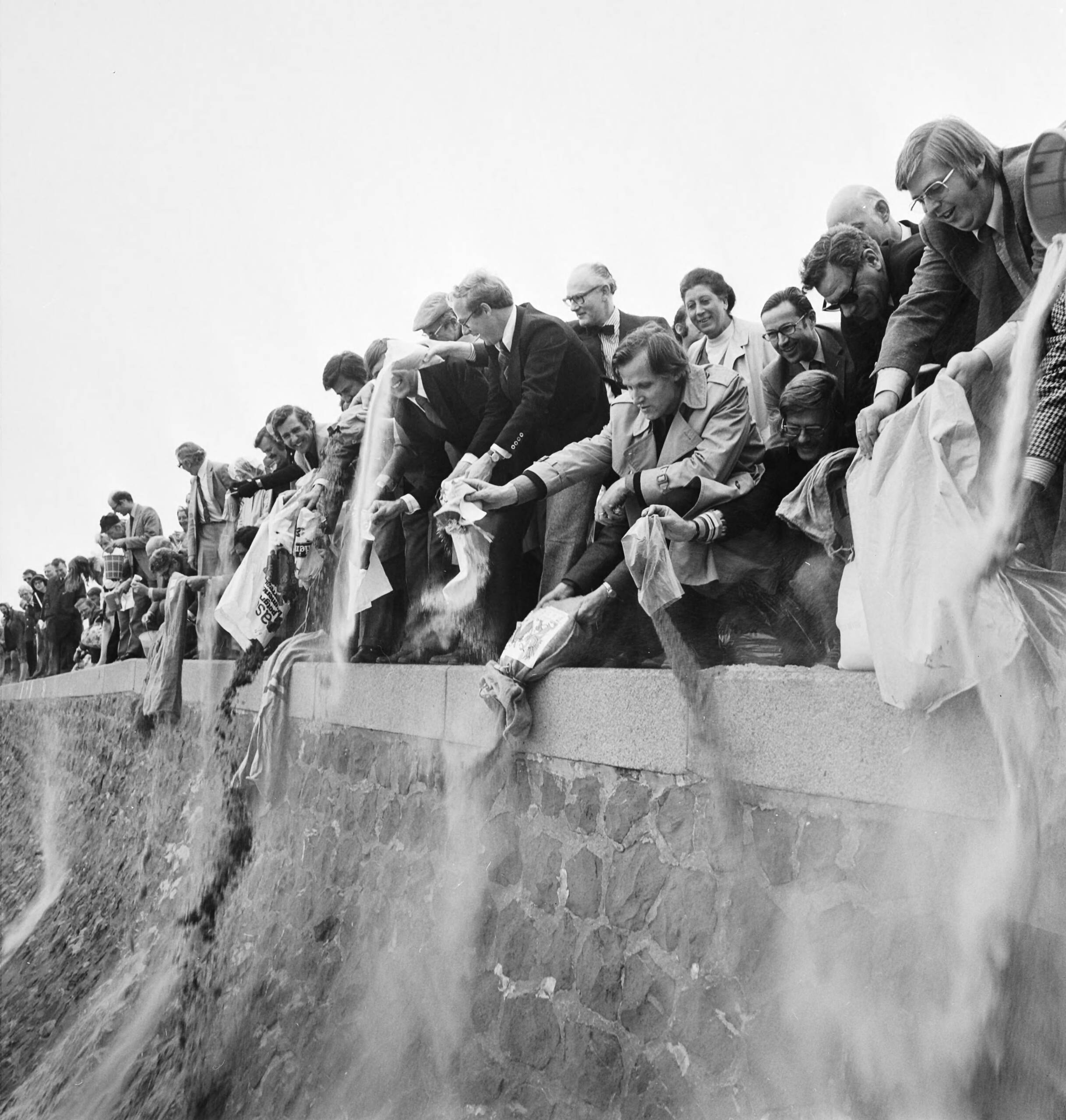 Fotocollectie Anefo — VVV-directeuren brengen zak zand naar jubilerende VVV in Scheveningen; VVV-directeuren storten zand op Scheveningse strand — Foto: Mieremet, Rob / Anefo. Licentie: Set B: Rechtenvrij / Publiek Domein. Bron: Nationaal Archief. http://hdl.handle.net/10648/ac4adf80-d0b4-102d-bcf8-003048976d84
