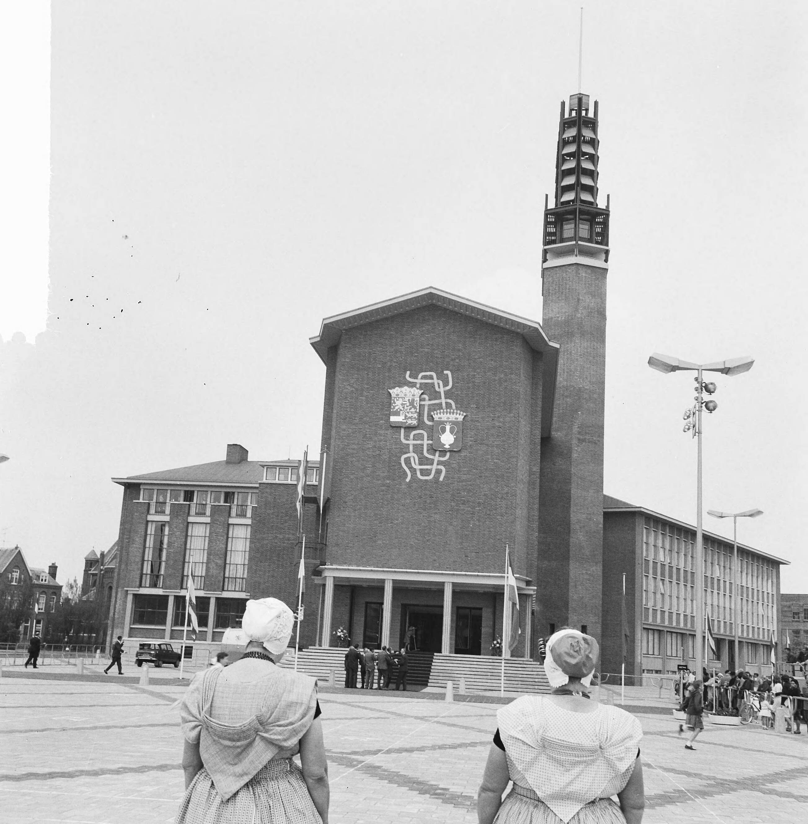 Koningin Juliana opent het nieuwe stadhuis te Vlissingen — Twee vrouwen in klederdracht kijken naar het nieuwe stadhuis — Foto: Nijs, Jac. de / Anefo. Licentie: Set B: Rechtenvrij / Publiek Domein. Bron: Nationaal Archief. http://hdl.handle.net/10648/34dd6407-eea8-24ba-2be7-0d30ed59ba8c