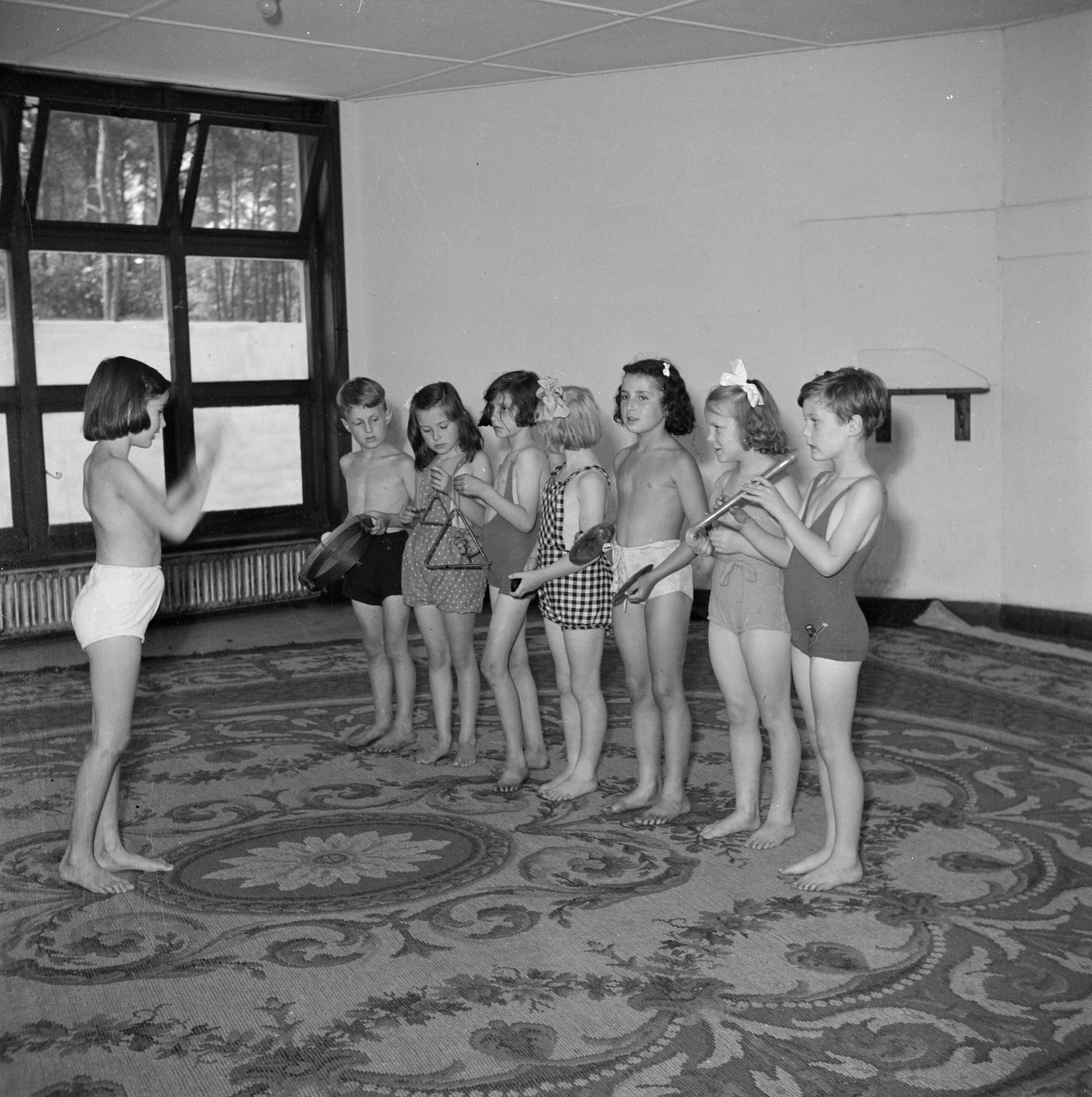 Prinses Beatrix en prinses Irene op de Werkplaats Kindergemeenschap van Kees Boeke te Bilthoven — Prinses Irene en klasgenoten maken muziek in gymkleding — Foto: Poll, Willem van de. Licentie: Set B: Rechtenvrij / Publiek Domein. Bron: Nationaal Archief. http://hdl.handle.net/10648/aee81244-d0b4-102d-bcf8-003048976d84