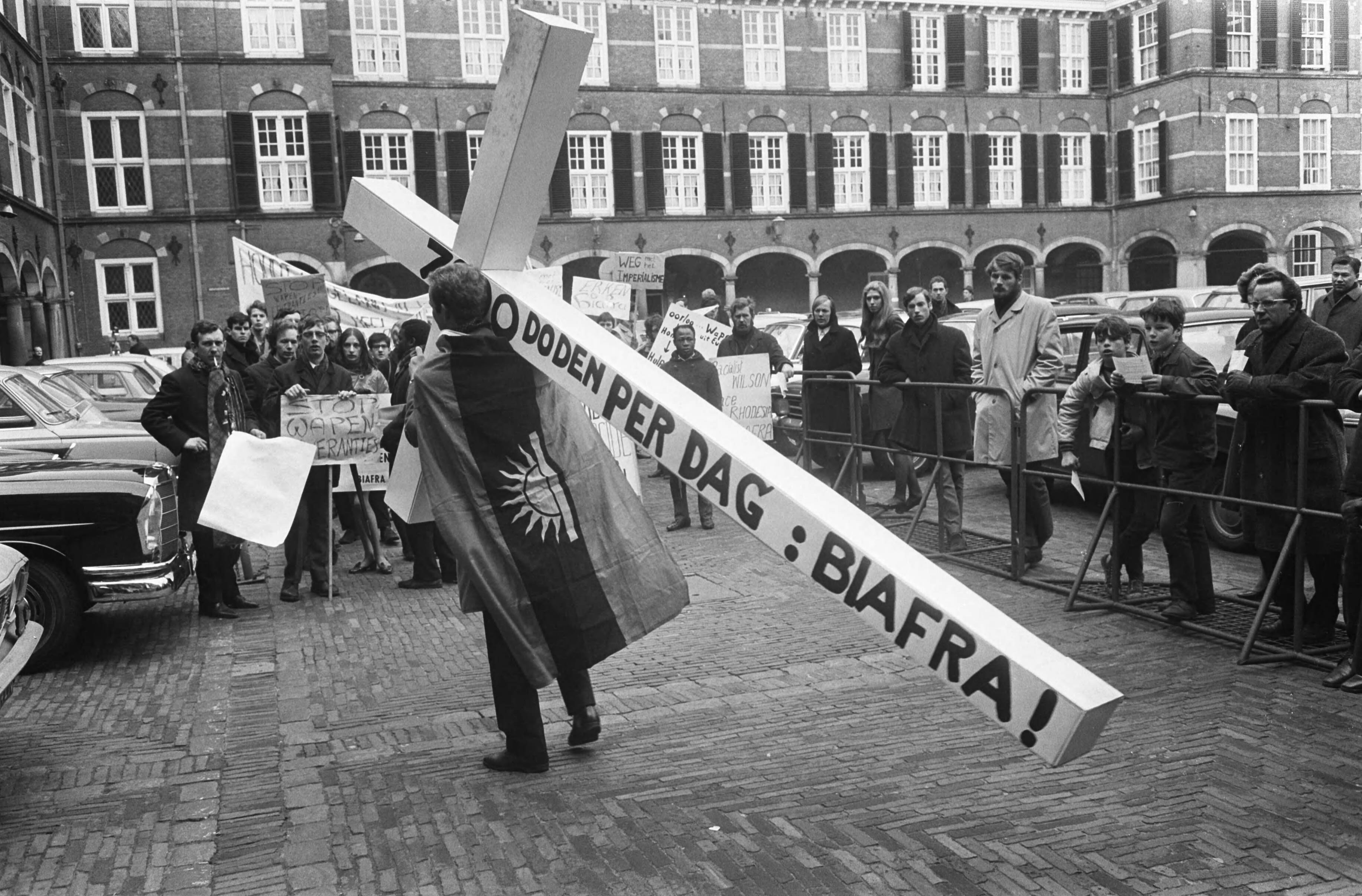 Fotocollectie Anefo — Demonstratie voor Biafra op Binnenhof Den Haag demonstrant met groot kruis — Foto: Koch, Eric / Anefo. Licentie: Set B: Rechtenvrij / Publiek Domein. Bron: Nationaal Archief. http://hdl.handle.net/10648/ab5fd47c-d0b4-102d-bcf8-003048976d84