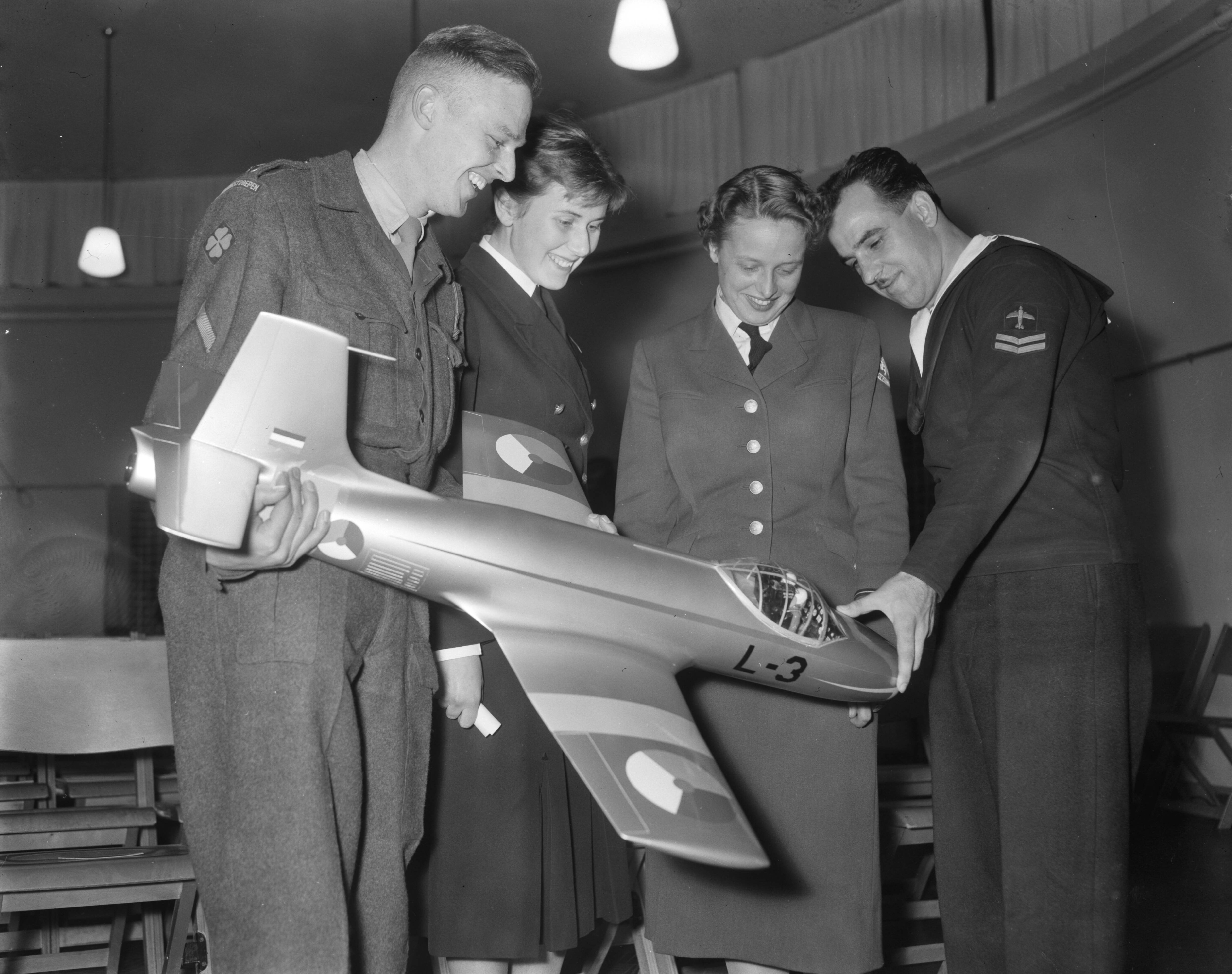 Fotocollectie Anefo — Nederlandse kampioenschappen vliegtuigherkenning bij Shell Den Haag. Vier deelnemers bekijken een vliegtuigmodel — Foto: Pot, Harry / Anefo. Licentie: Set B: Rechtenvrij / Publiek Domein. Bron: Nationaal Archief. http://hdl.handle.net/10648/a951a3fe-d0b4-102d-bcf8-003048976d84