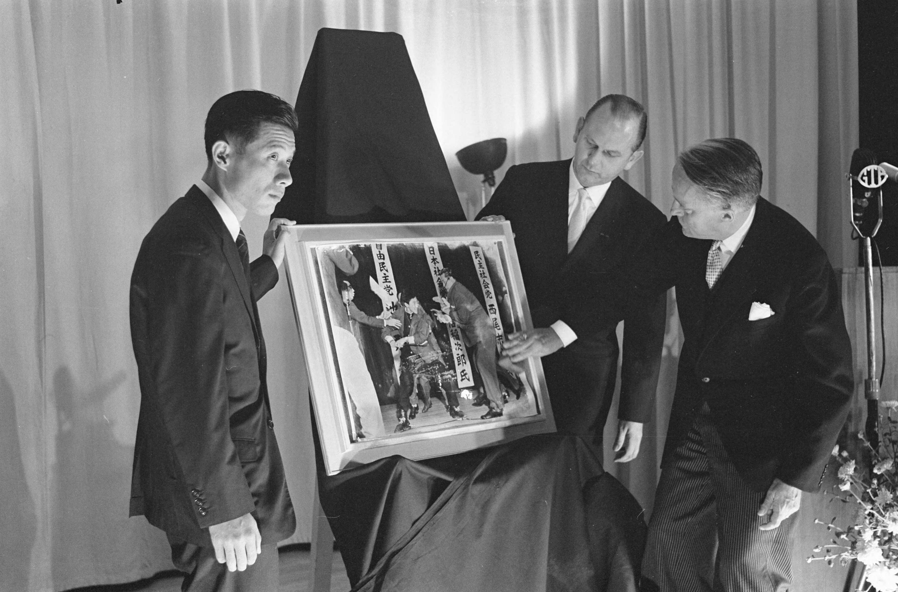 Fotocollectie Anefo — Opening World Press Photo 1961. Commissaris der Koningin in Zuid-Holland mr. J. Klaasesz en de Japanse fotograaf Yasushi Nagao met de winnende foto. Tussen hen in voorzitter Peter van Breukelen — Foto: Pot, Harry / Anefo. Licentie: Set B: Rechtenvrij / Publiek Domein. Bron: Nationaal Archief. http://hdl.handle.net/10648/a9e4ef92-d0b4-102d-bcf8-003048976d84