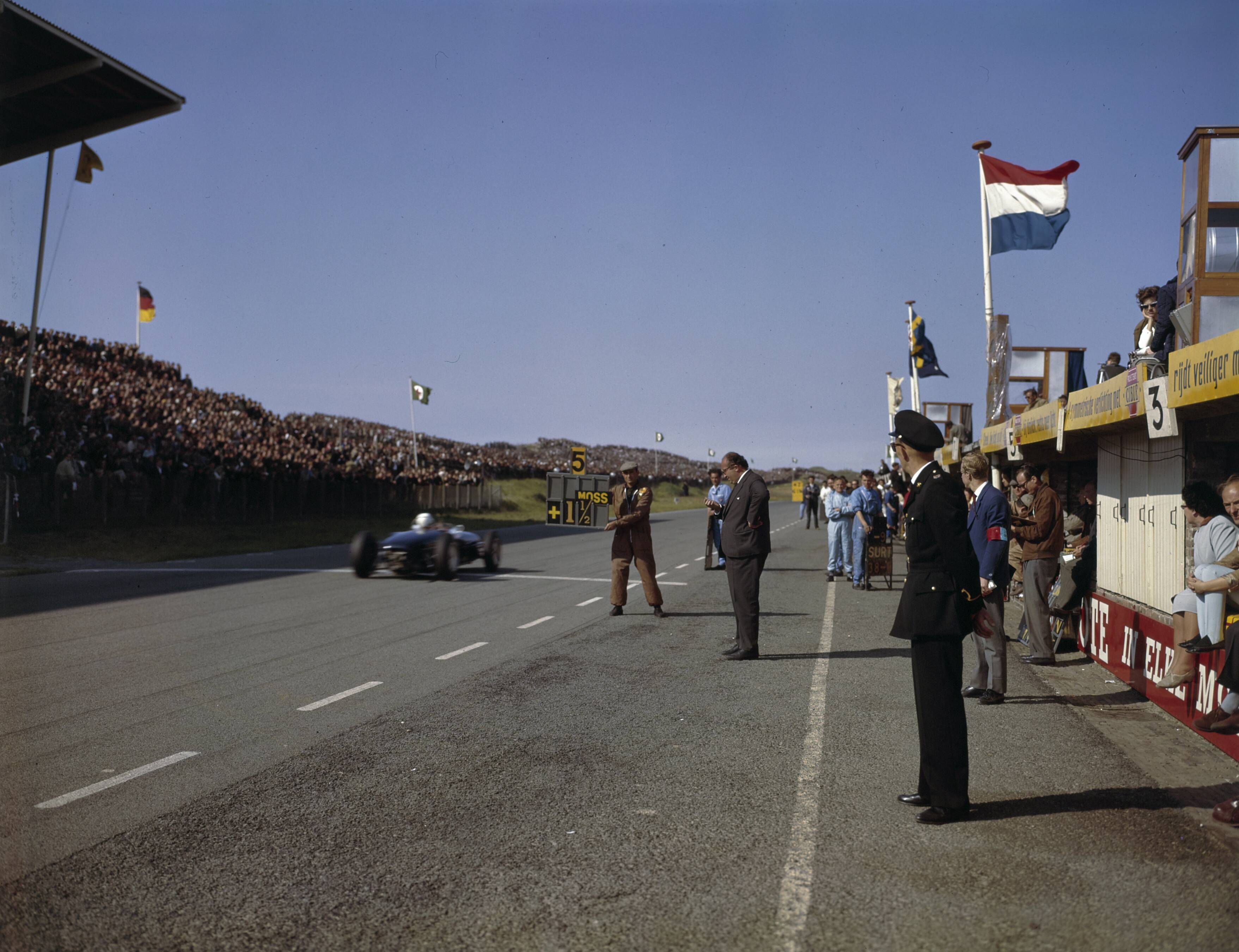 Fotocollectie Anefo — [Grand Prix Zandvoort 1961. Man houdt bord op met mededeling "5 Moss +1 1/2. Een raceauto passeert de finishlijn] — Foto: Fotograaf Onbekend / Anefo. Licentie: Set B: Rechtenvrij / Publiek Domein. Bron: Nationaal Archief. http://hdl.handle.net/10648/ad8cd4a2-d0b4-102d-bcf8-003048976d84