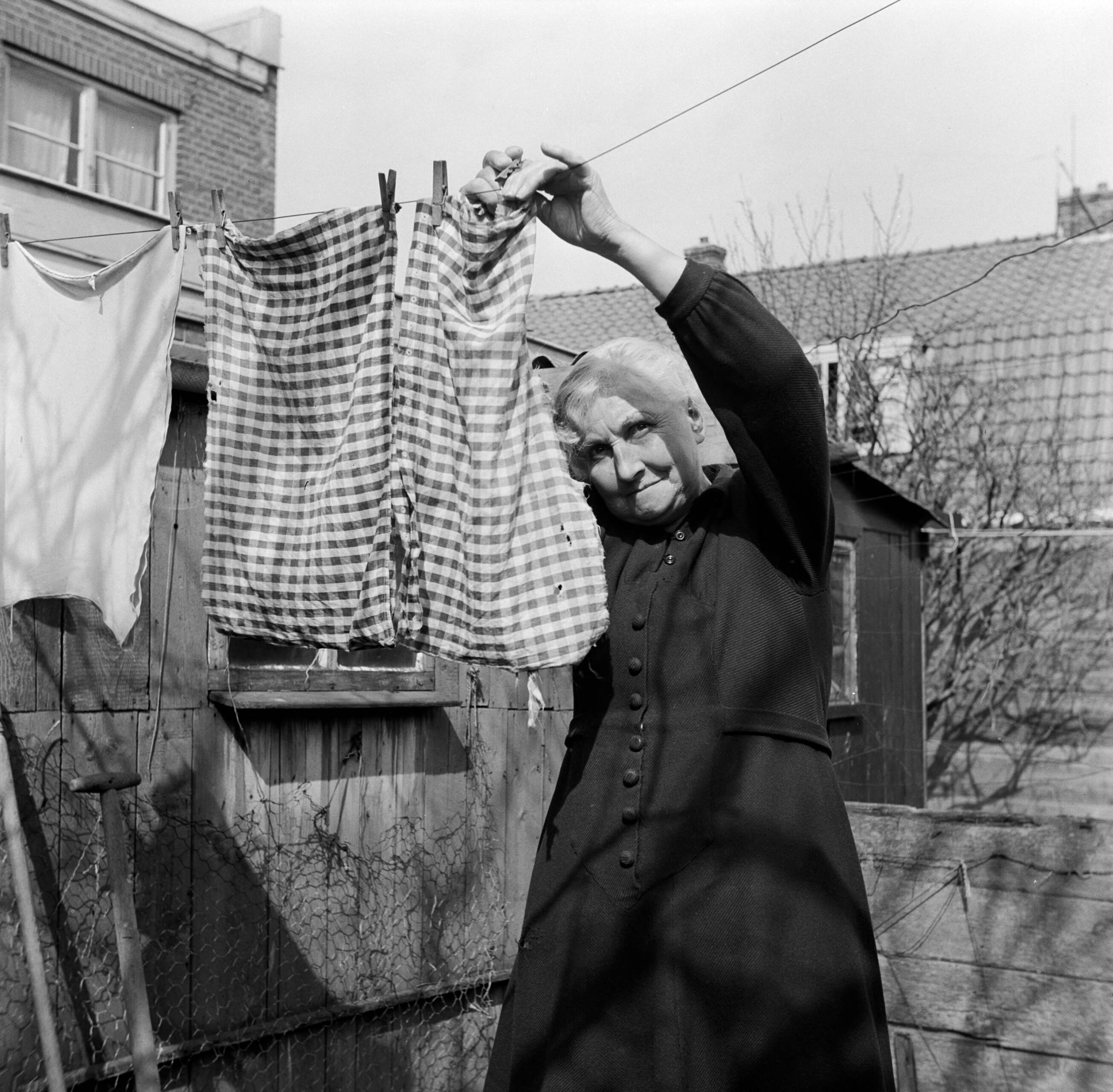 Fotocollectie Van de Poll — Moeder De Jong hangt de was op in de achtertuin van hun woning in Huizum (nu deel van Leeuwarden) — Foto: Poll, Willem van de. Licentie: Set B: Rechtenvrij / Publiek Domein. Bron: Nationaal Archief. http://hdl.handle.net/10648/aeccc7f0-d0b4-102d-bcf8-003048976d84