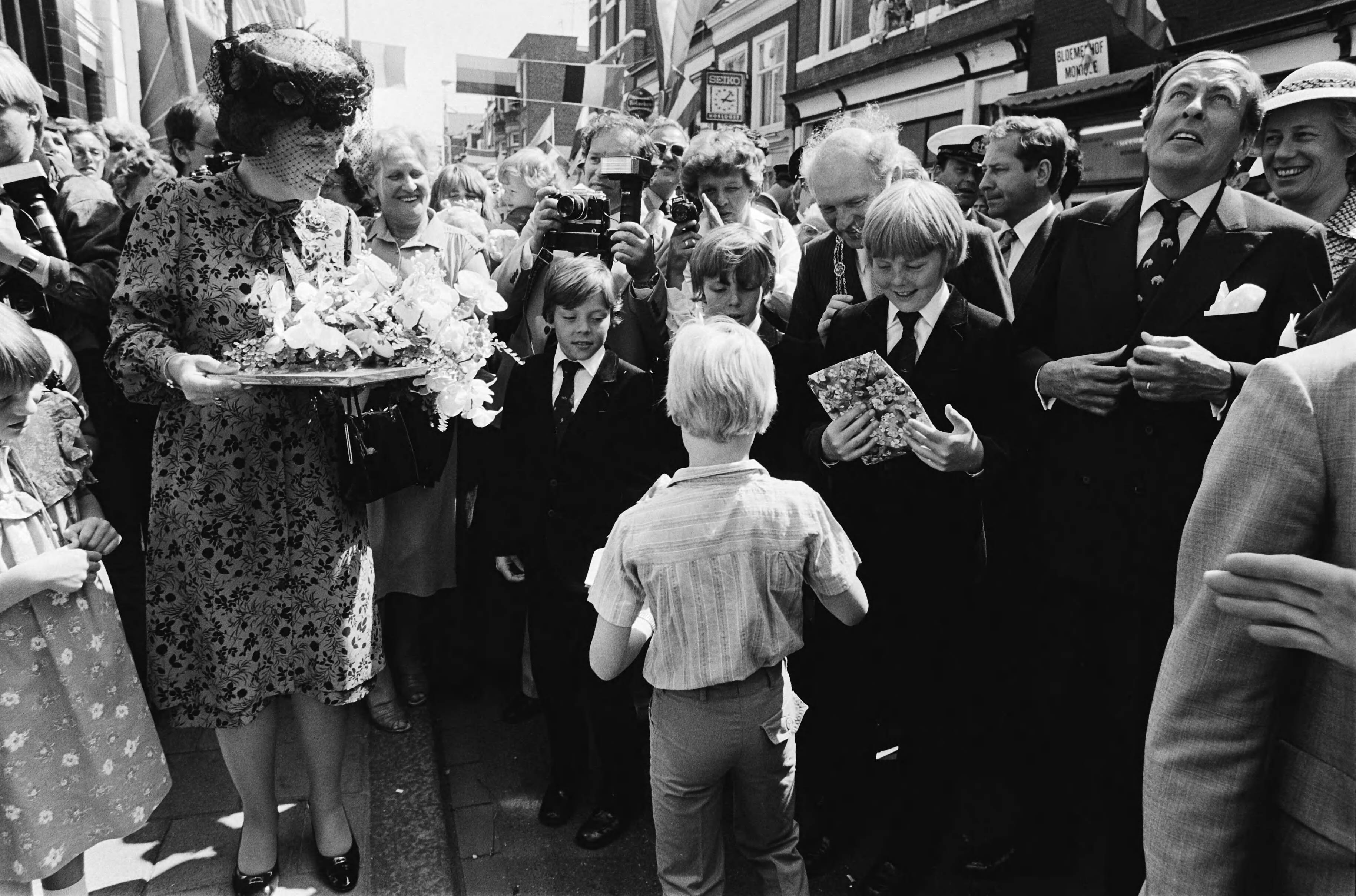 Fotocollectie Anefo — Intocht Koningin Beatrix in Den Haag in open caleche; overzicht drukte tijdens wandeling Koninklijke familie in Scheveningen, cadeautjes voor Prinsjes — Foto: Croes, Rob C. / Anefo. Licentie: Set B: Rechtenvrij / Publiek Domein. Bron: Nationaal Archief. http://hdl.handle.net/10648/ace0ddb4-d0b4-102d-bcf8-003048976d84