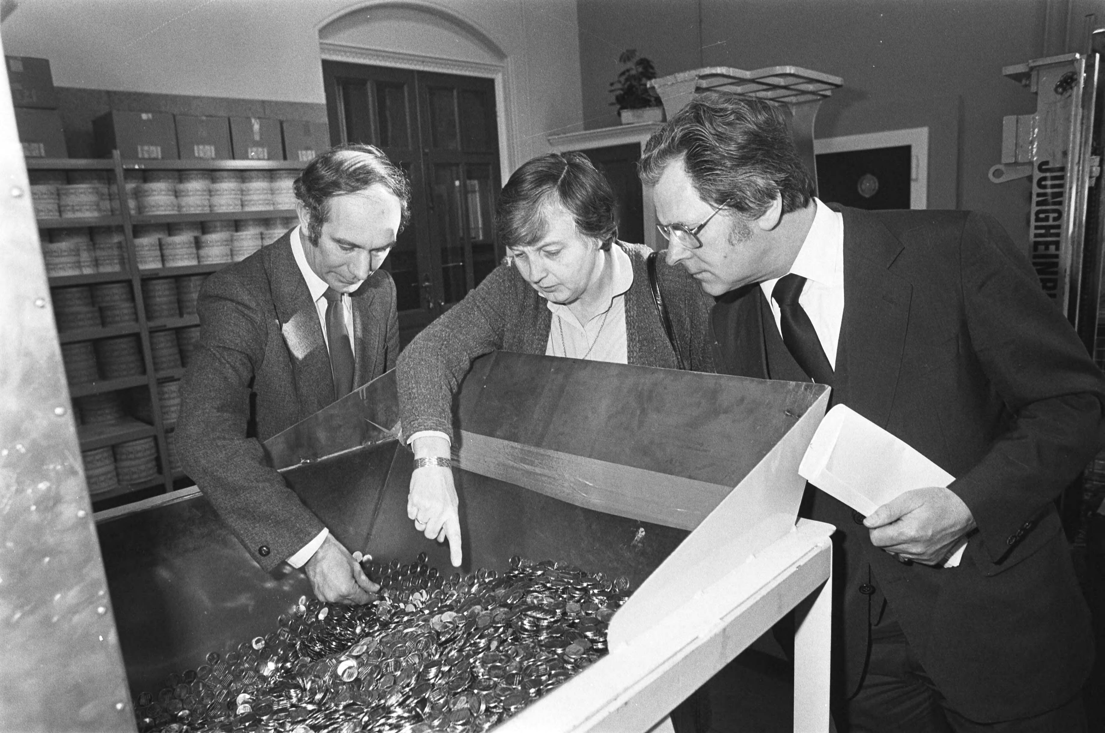 Fotocollectie Anefo — Leden Vaste Kamercom. voor Financien bezoeken de Rijksmunt Utrecht. Mw Epema Brugman (PVDA) en De Graaf (CDA) bij bak nieuwe guldens — Foto: Dijk, Hans van / Anefo. Licentie: Set B: Rechtenvrij / Publiek Domein. Bron: Nationaal Archief. http://hdl.handle.net/10648/ad0f1db4-d0b4-102d-bcf8-003048976d84