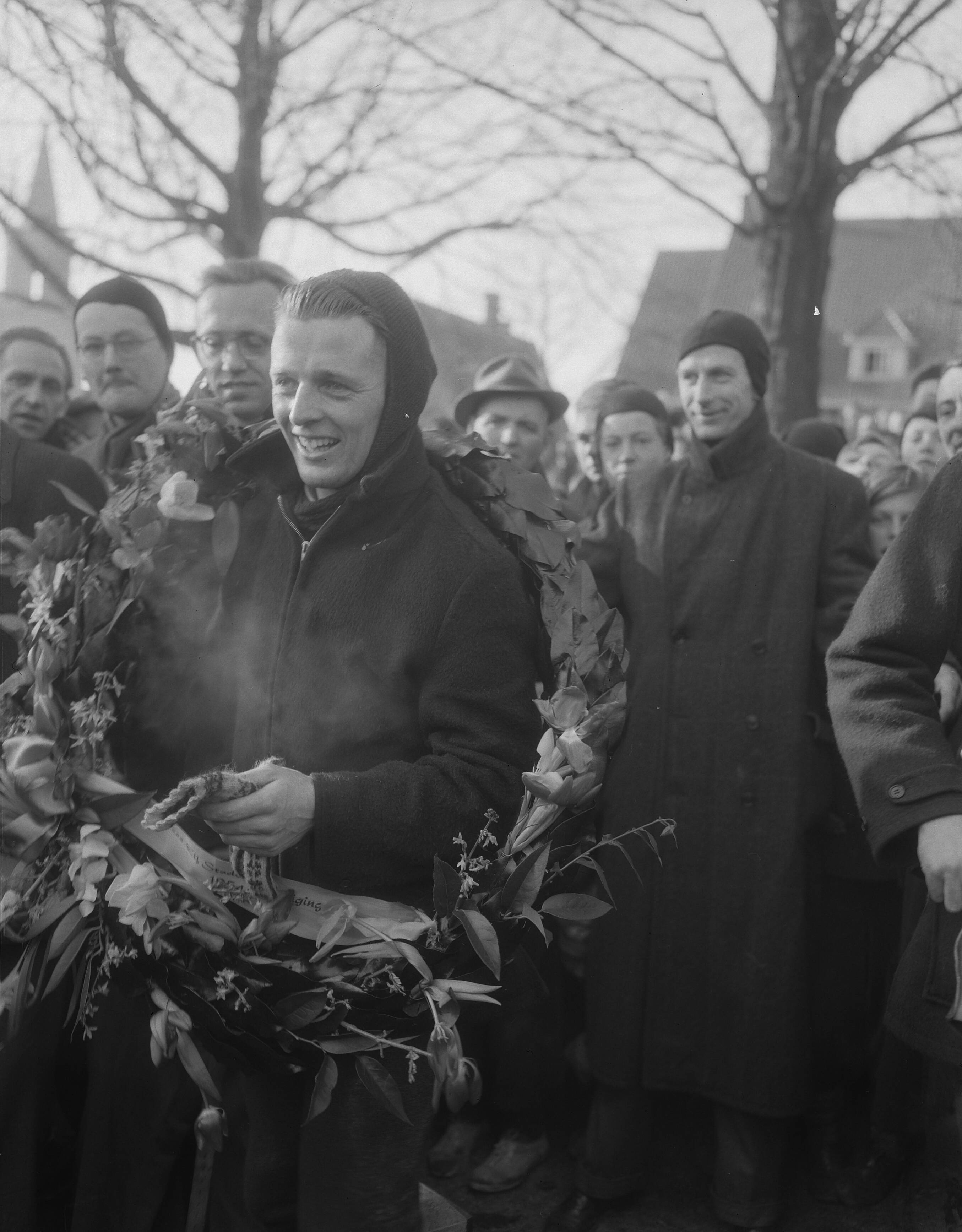 Elfstedentocht 1954 — Elfstedentocht. Jeen van den Berg gaat als eerste over de finish — Foto: Duinen, G.W. van / Anefo. Licentie: Set B: Rechtenvrij / Publiek Domein. Bron: Nationaal Archief. http://hdl.handle.net/10648/a91c6752-d0b4-102d-bcf8-003048976d84