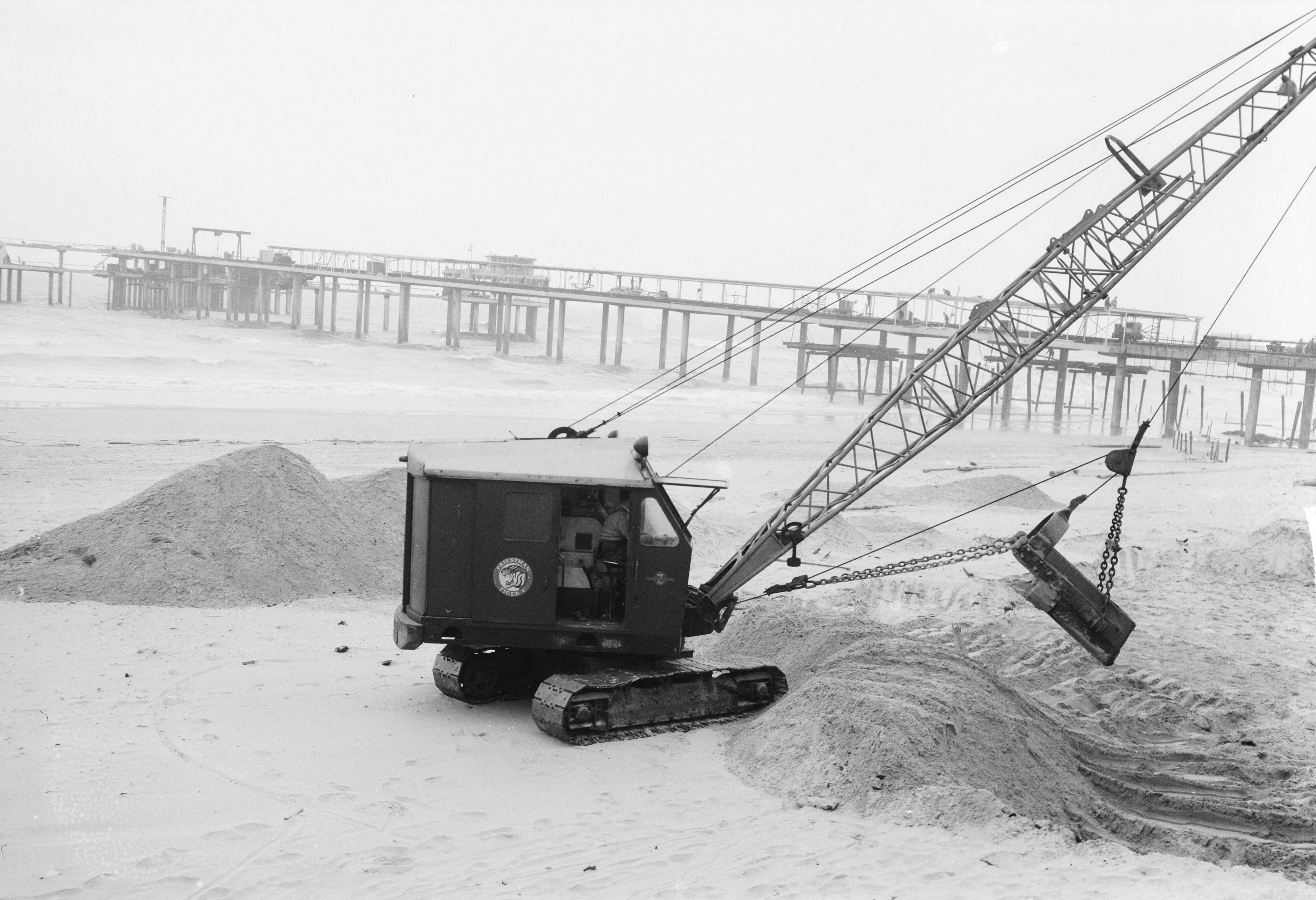 Fotocollectie Anefo — Egaliseren van het strand te Scheveningen voor het komend badseizoen — Foto: Behrens, Herbert F. / Anefo. Licentie: Set B: Rechtenvrij / Publiek Domein. Bron: Nationaal Archief. http://hdl.handle.net/10648/a9ccf13a-d0b4-102d-bcf8-003048976d84