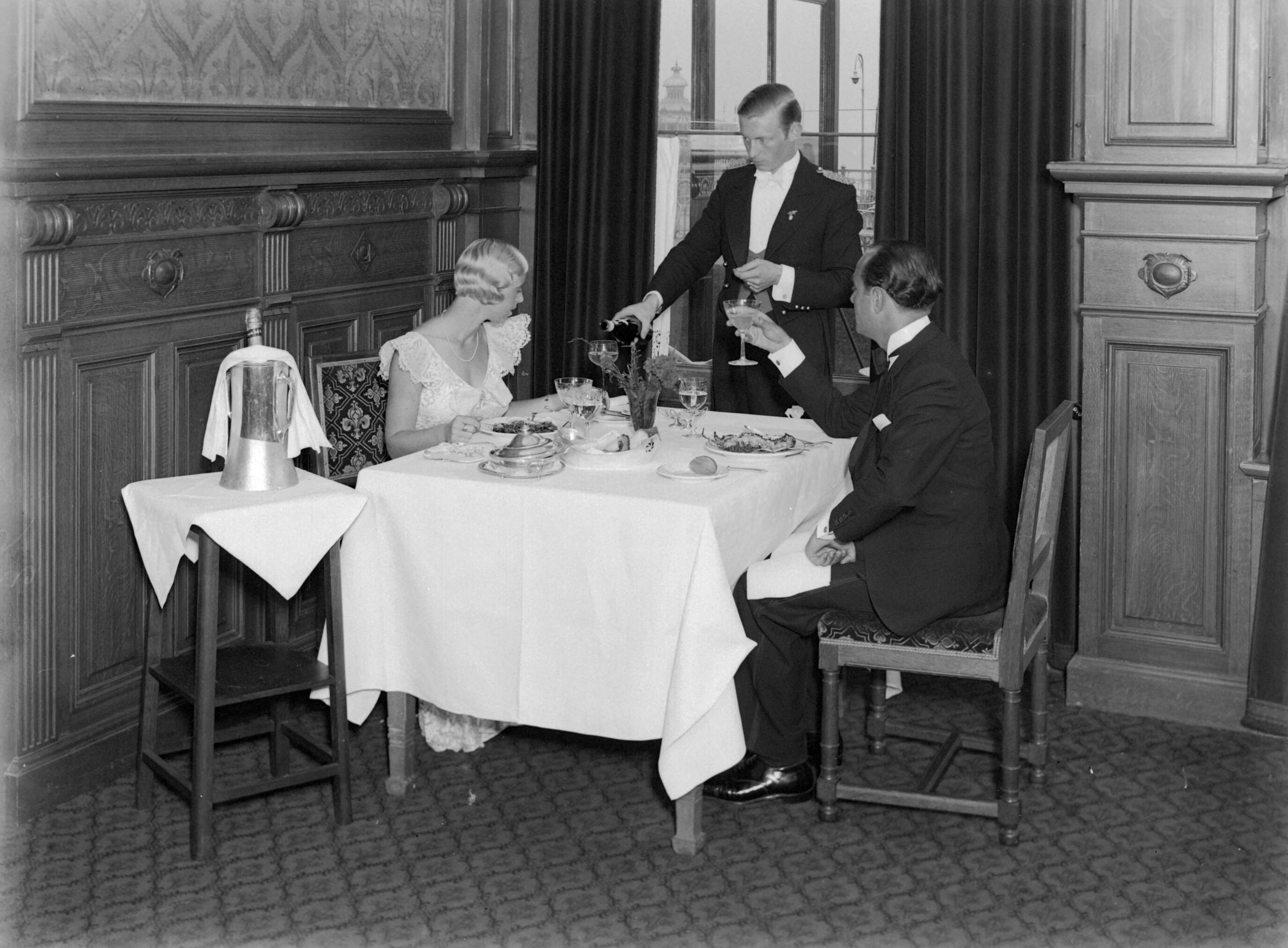 Scheveningen. — Een man (Farrar?) en een vrouw (Yvonne?) bij het diner in het Palace Hotel in Scheveningen — Foto: Poll, Willem van de. Licentie: Set B: Rechtenvrij / Publiek Domein. Bron: Nationaal Archief. http://hdl.handle.net/10648/ae9abe36-d0b4-102d-bcf8-003048976d84