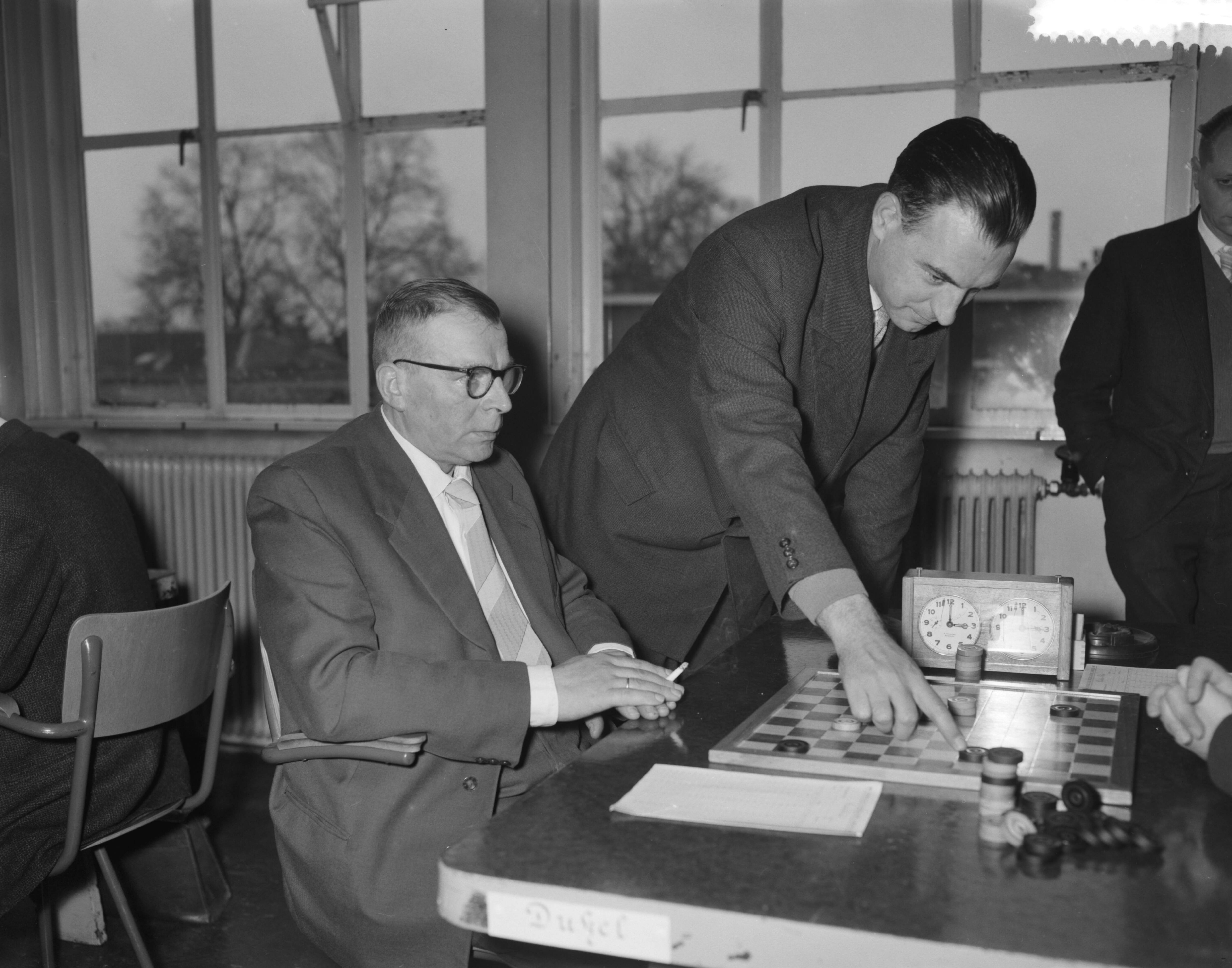 Fotocollectie Anefo — Damkampioenschap van Nederland te Utrecht. B. Dukel (links) en Ir. G. E. Van Dijk — Foto: Bilsen, Joop van / Anefo. Licentie: Set B: Rechtenvrij / Publiek Domein. Bron: Nationaal Archief. http://hdl.handle.net/10648/a98e2bee-d0b4-102d-bcf8-003048976d84