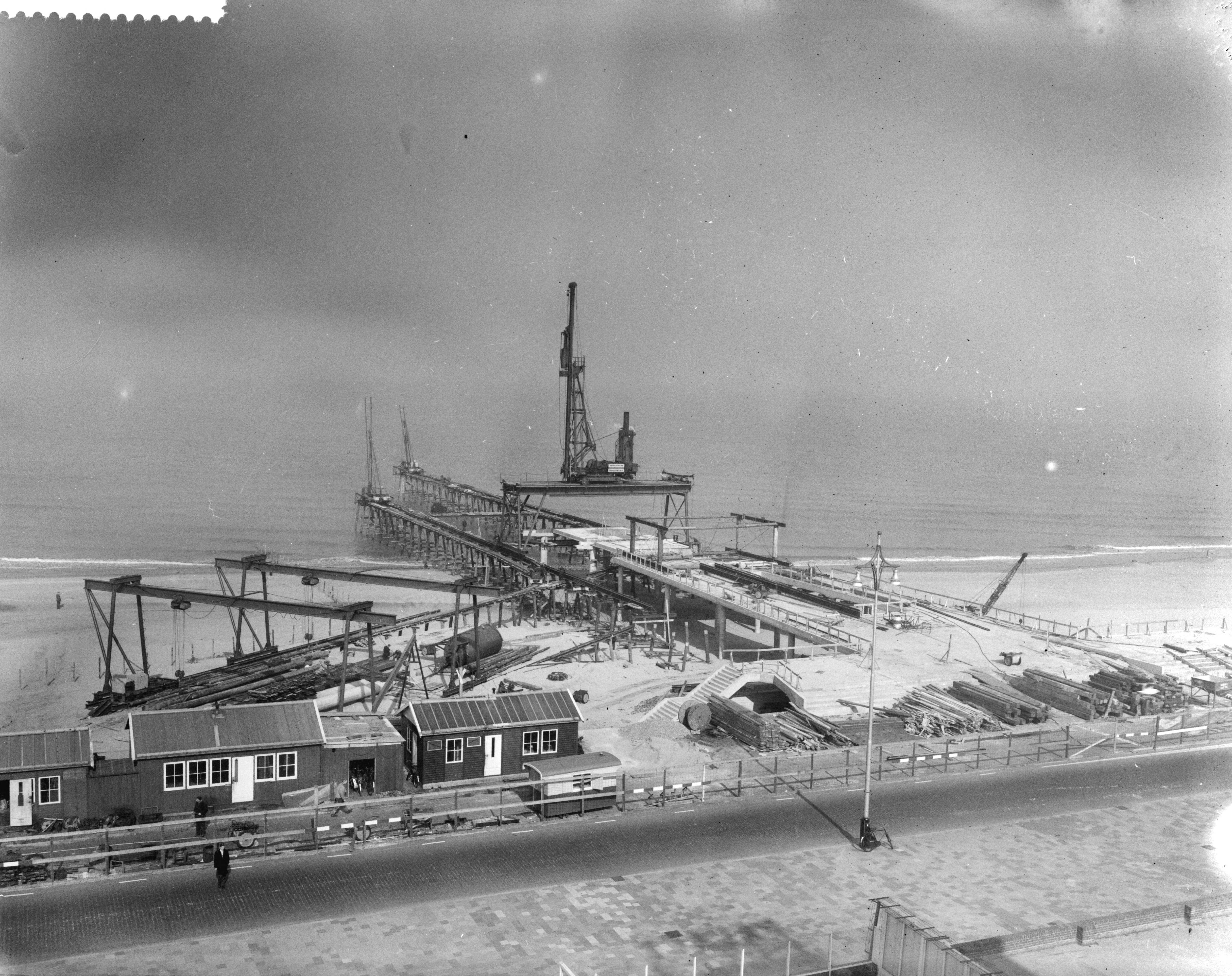 Fotocollectie Anefo — Bouw pier te Scheveningen — Foto: Behrens, Herbert F. / Anefo. Licentie: Set B: Rechtenvrij / Publiek Domein. Bron: Nationaal Archief. http://hdl.handle.net/10648/a9aad118-d0b4-102d-bcf8-003048976d84