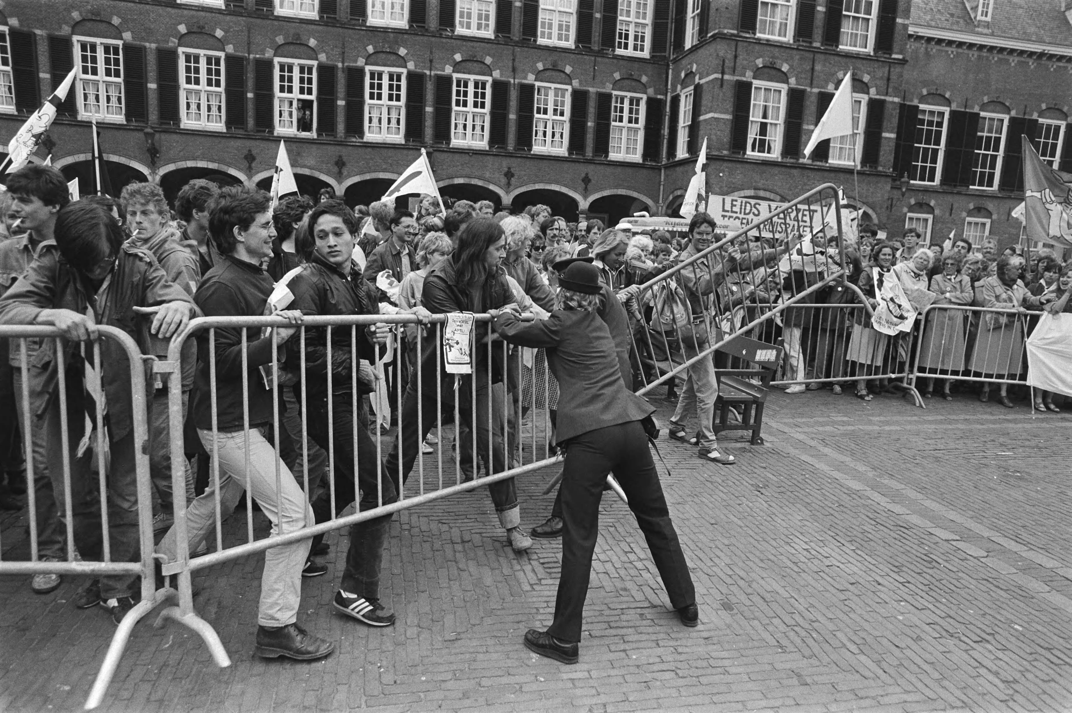 Fotocollectie Anefo — Demonstranten tegen kernwapens in Den Haag ivm debat in Tweede Kamer over kruisrakettenplaatsing; politie duwt tegen hekken om demonstranten Binnenhof — Foto: Antonisse, Marcel / Anefo. Licentie: Set B: Rechtenvrij / Publiek Domein. Bron: Nationaal Archief. http://hdl.handle.net/10648/ad39f39a-d0b4-102d-bcf8-003048976d84
