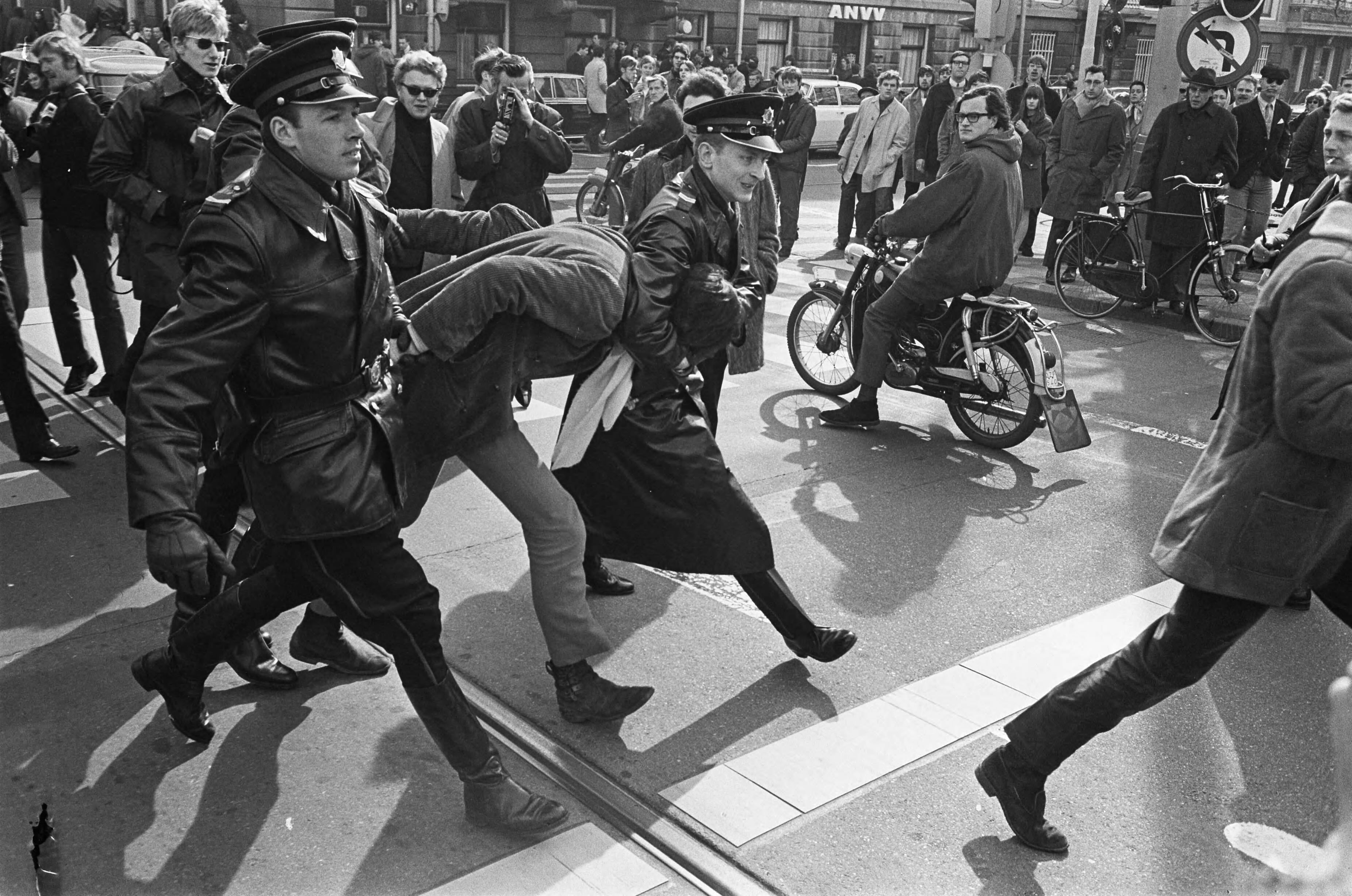 Fotocollectie Anefo — Pro Amerika demonstratie in Den Haag . Een tegen-demonstrant wordt door de politie opgebracht — Foto: Koch, Eric / Anefo. Licentie: Set B: Rechtenvrij / Publiek Domein. Bron: Nationaal Archief. http://hdl.handle.net/10648/ab39b698-d0b4-102d-bcf8-003048976d84