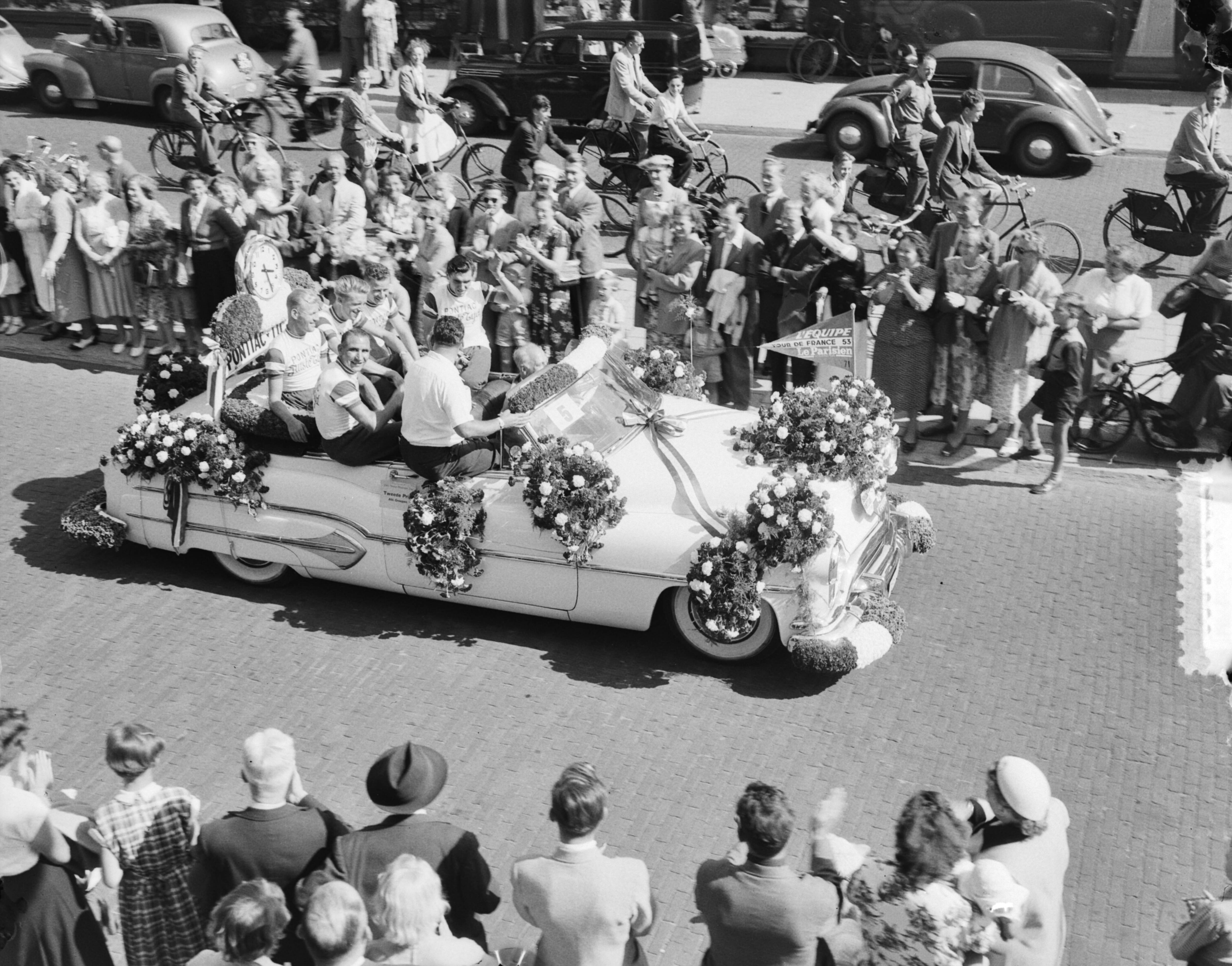 Bloemencorso in Den Haag 1953 — Bloemencorso in Den Haag. Tour de France ploeg in wagen — Foto: Duinen, G.W. van / Anefo. Licentie: Set B: Rechtenvrij / Publiek Domein. Bron: Nationaal Archief. http://hdl.handle.net/10648/a910bc68-d0b4-102d-bcf8-003048976d84