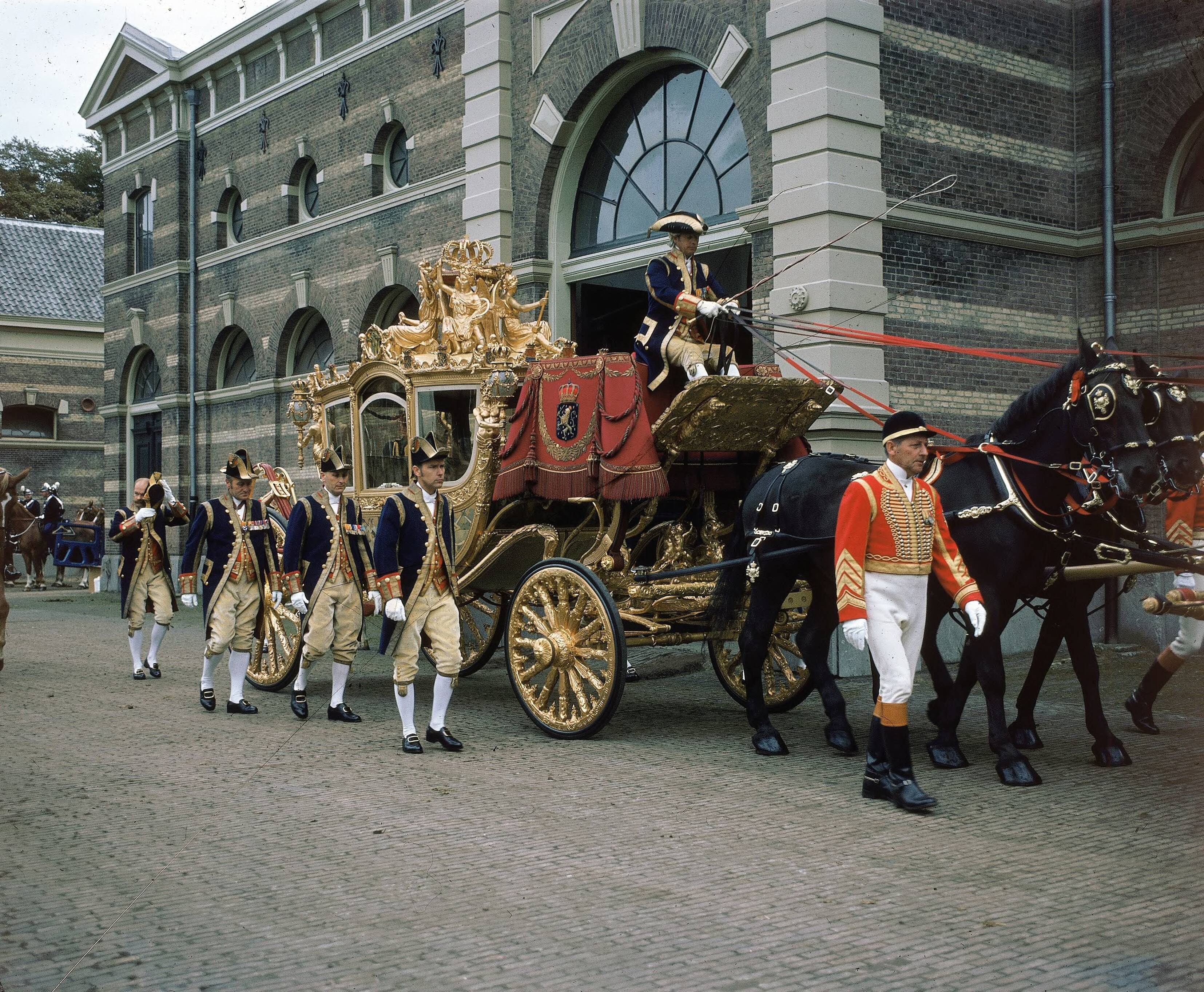 Fotocollectie RVD / Koninklijk Huis — Prinsjesdag - Gouden koets, met koetsier, lakeien, stalpersoneel en paarden op de binnenplaats van de koninklijke stallen aan de Noordwal te Den Haag — Foto: Mastenbroek, Cees / RVD. Licentie: Set B: Rechtenvrij / Publiek Domein. Bron: Nationaal Archief. http://hdl.handle.net/10648/afb272a0-d0b4-102d-bcf8-003048976d84
