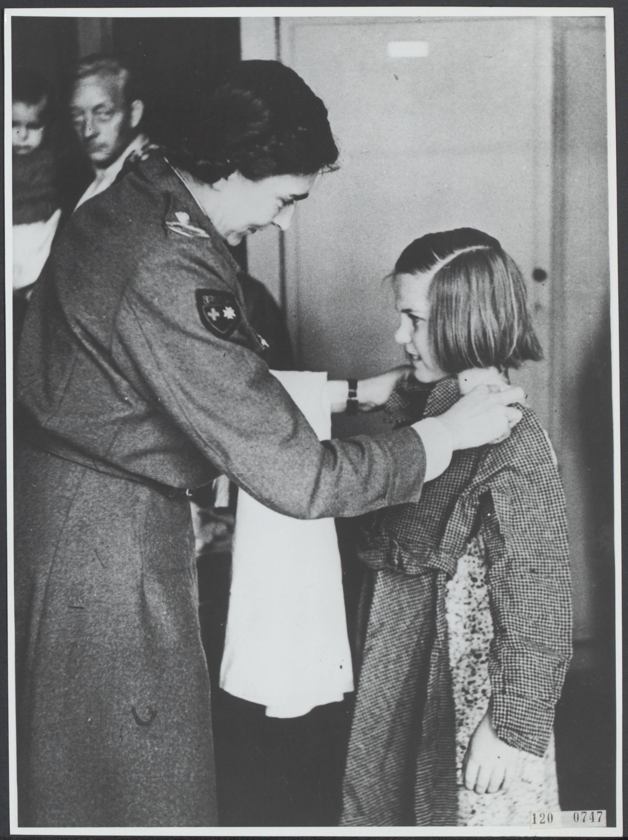 Hongerwinter 1944/1945 — Hongerwinter. Den Haag. Een meisje krijgt nieuwe kleding aangepast door een medewerker van het Rode Kruis — Foto: Rousel (repro) / RVD. Licentie: Set B: Rechtenvrij / Publiek Domein. Bron: Nationaal Archief. http://hdl.handle.net/10648/af2240f4-d0b4-102d-bcf8-003048976d84