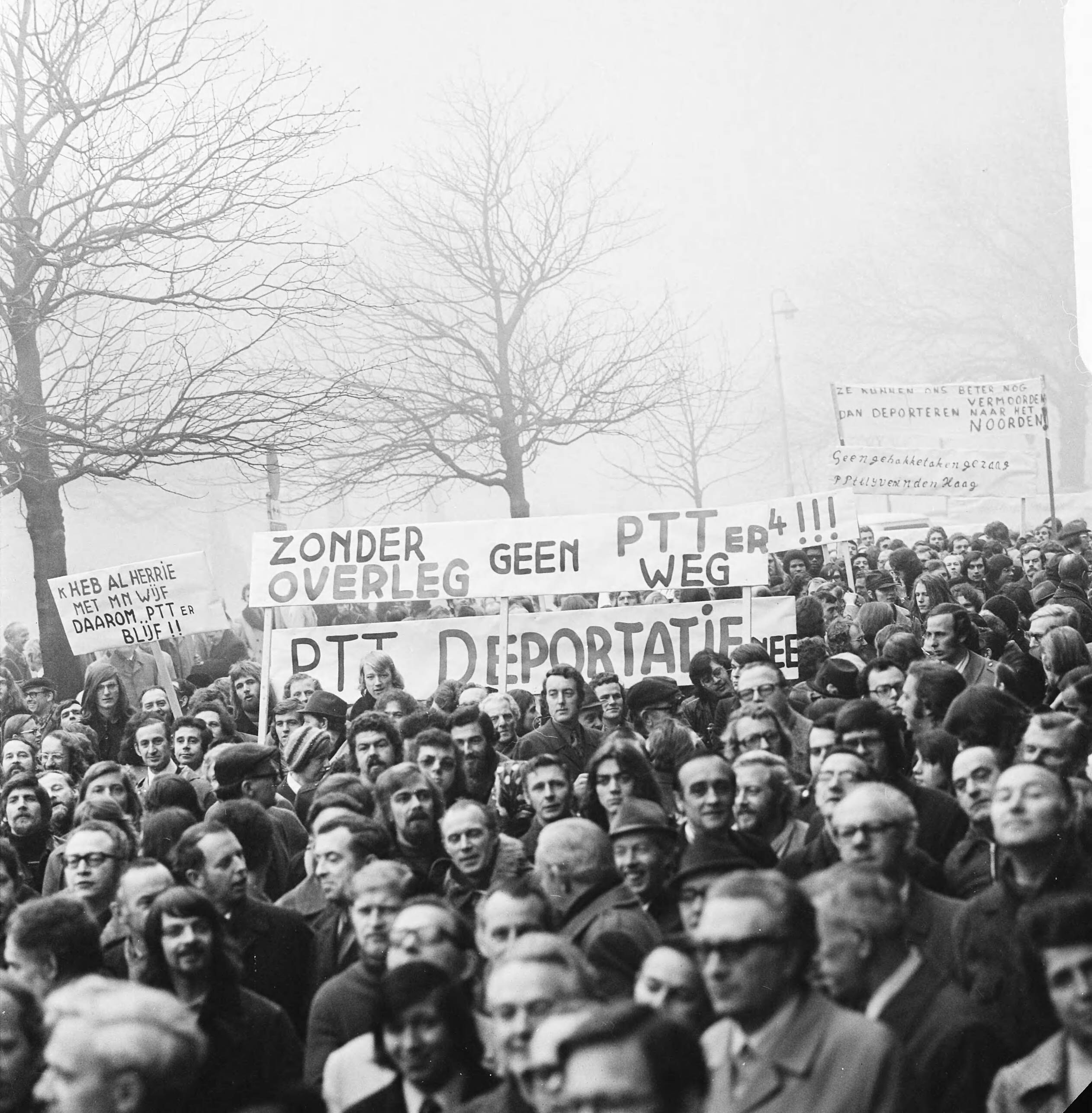 PTT-ers demonstreren in Den Haag voor het kantoor van de PTT i.v.m de voorgenomen verhuizing naar Groningen — Demonstranten met spandoeken — Foto: Mieremet, Rob / Anefo. Licentie: Set B: Rechtenvrij / Publiek Domein. Bron: Nationaal Archief. http://hdl.handle.net/10648/ac45540c-d0b4-102d-bcf8-003048976d84