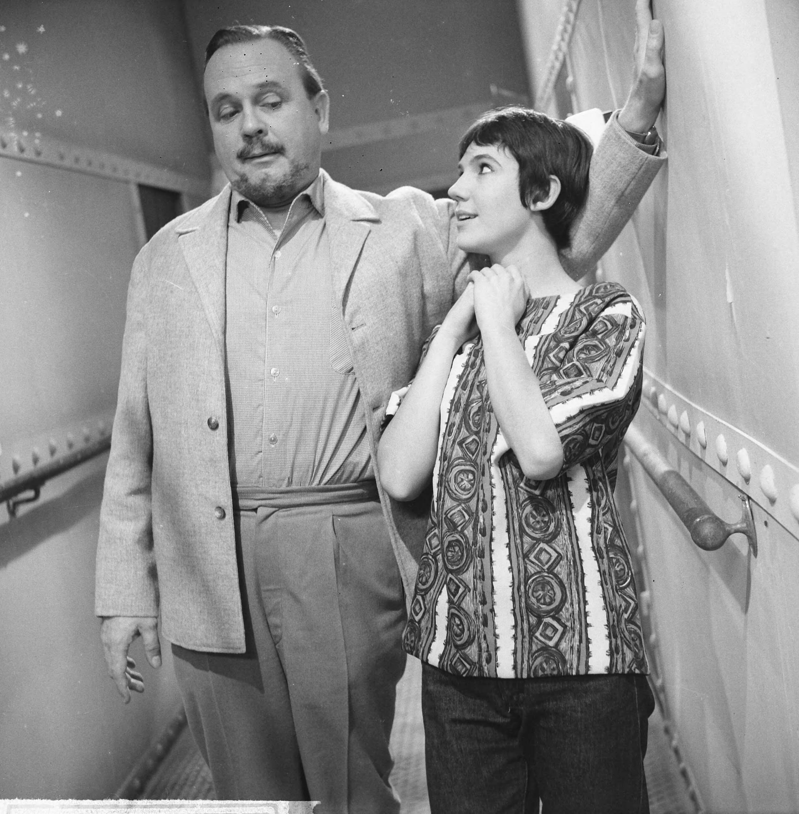 Fotocollectie Anefo — Opname televisiespel "Met 24 pk door Europa" (uitzending niet doorgegaan). Guus Verstraete jr. en Simone RooskensNegatieven zijn een jaar later, op 31-3-1964, geregistreerd in fotoadministratie Anefo! Deze aflevering is wél uitgezonden, als eerste op 20-10-1963. Op 22-11-1963 schrijft Trouw: Er komen geen afleveringen meer van de televisiestrip "Met 24 P.K. door Europa" met Ko van Dijk, Teddy Schaank en Simone Rooskens. De AVRO heeft besloten de serie te staken. Reden: de strip kon ook na bewerking van het oorspronkelijke script niet aan de gestelde eisen voldoen. Karel Prior, hoofd amusementsprogramma's van de AVRO zei van deze door het echtpaar Mazure geschreven strip, dat ze „te filmisch" waren geschreven, waardoor men er in de televisiestudio's niet goed mee uit de voeten kon. Ellen en Georges Mazure, die zes afleveringen van hun strip aan de AVRO verkochten, liggen al een poosje overhoop met de AVRO in verband met de televisie-uitzendingen van hun script. Voo