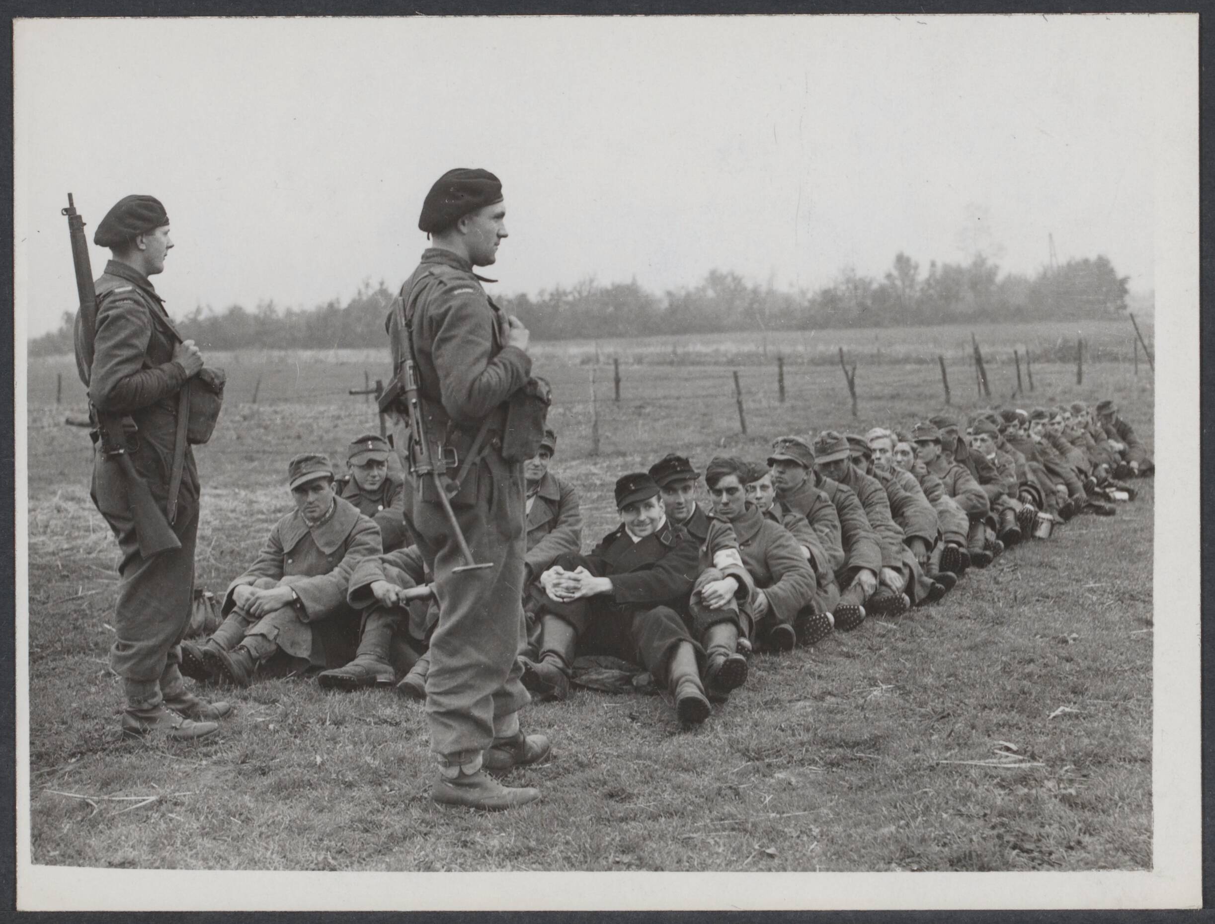 Nederland front, 1944 — Poolse leger aan het front Breda-Tilburg. Na de verovering van Alphen en Gilze. Poolse bewakers en Duitse krijgsgevangen die dicht op elkaar zitten om ontsnapping te voorkomen — Foto: Keystone / Rechtenvrij. Licentie: Set B: Rechtenvrij / Publiek Domein. Bron: Nationaal Archief. http://hdl.handle.net/10648/d24d5d07-b207-9ecc-4a5b-7295f2194226