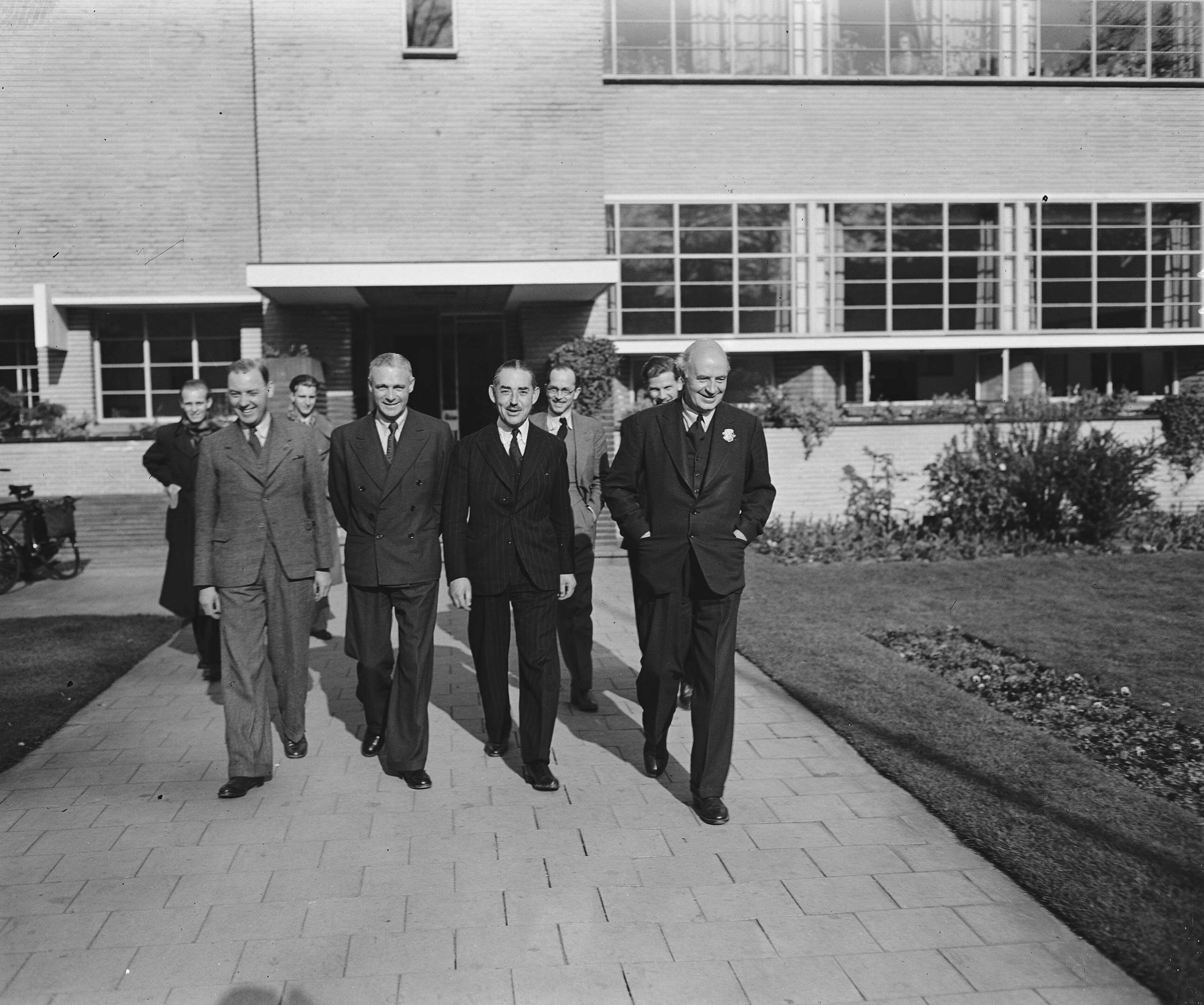 Fotocollectie Anefo — Delegatie van de BBC bezoekt Nederland. BBC-omroepers in Hilversum. Vlnr Frank Gillard, ?, John Snagge, ? — Foto: Raucamp, Koos / Anefo. Licentie: Set B: Rechtenvrij / Publiek Domein. Bron: Nationaal Archief. http://hdl.handle.net/10648/a89cde4c-d0b4-102d-bcf8-003048976d84