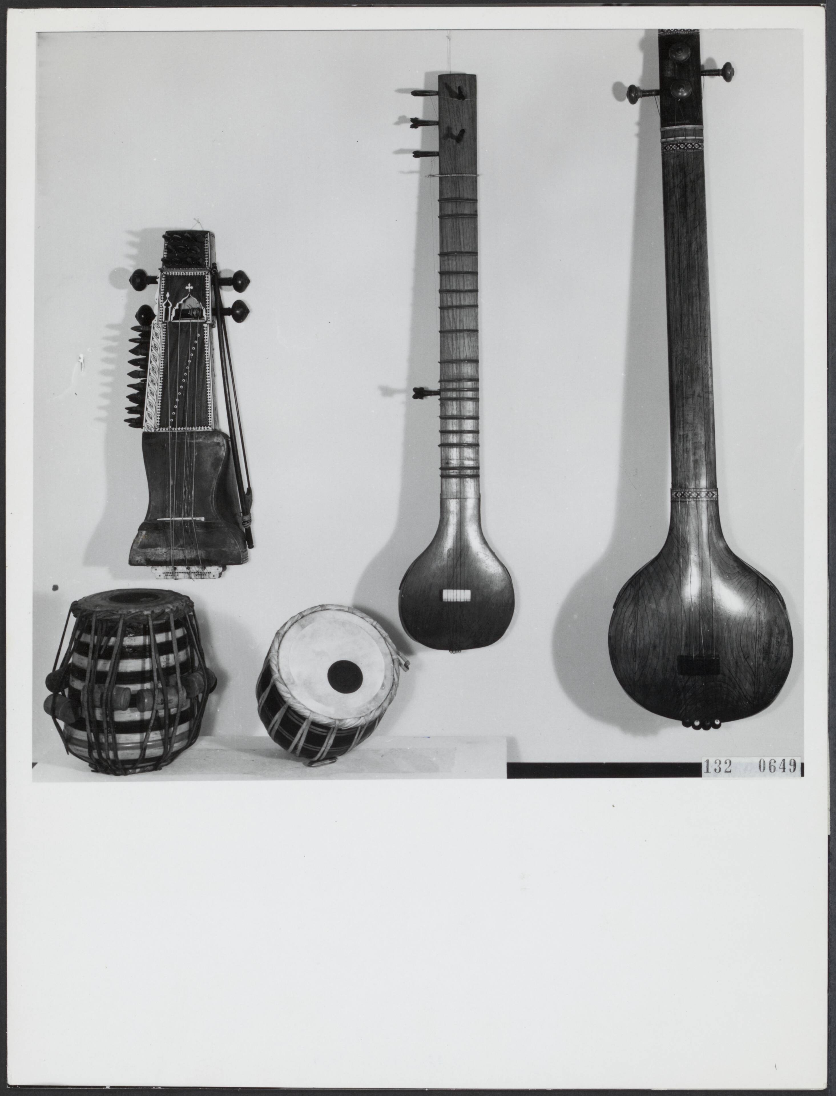 Fotocollectie Rijksvoorlichtingsdienst Eigen — Enkele instrumenten uit de India-collectie van het Haags Gemeentemuseum. Vlnr. Sarangi (strijkinstrument), Sitar (tokkelinstrument), Tanpura (tokkelinstrument) en onder Tabla (twee trommen) — Foto: Fotodienst Gemeente Den Haag. Licentie: Set B: Rechtenvrij / Publiek Domein. Bron: Nationaal Archief. http://hdl.handle.net/10648/af54757e-d0b4-102d-bcf8-003048976d84