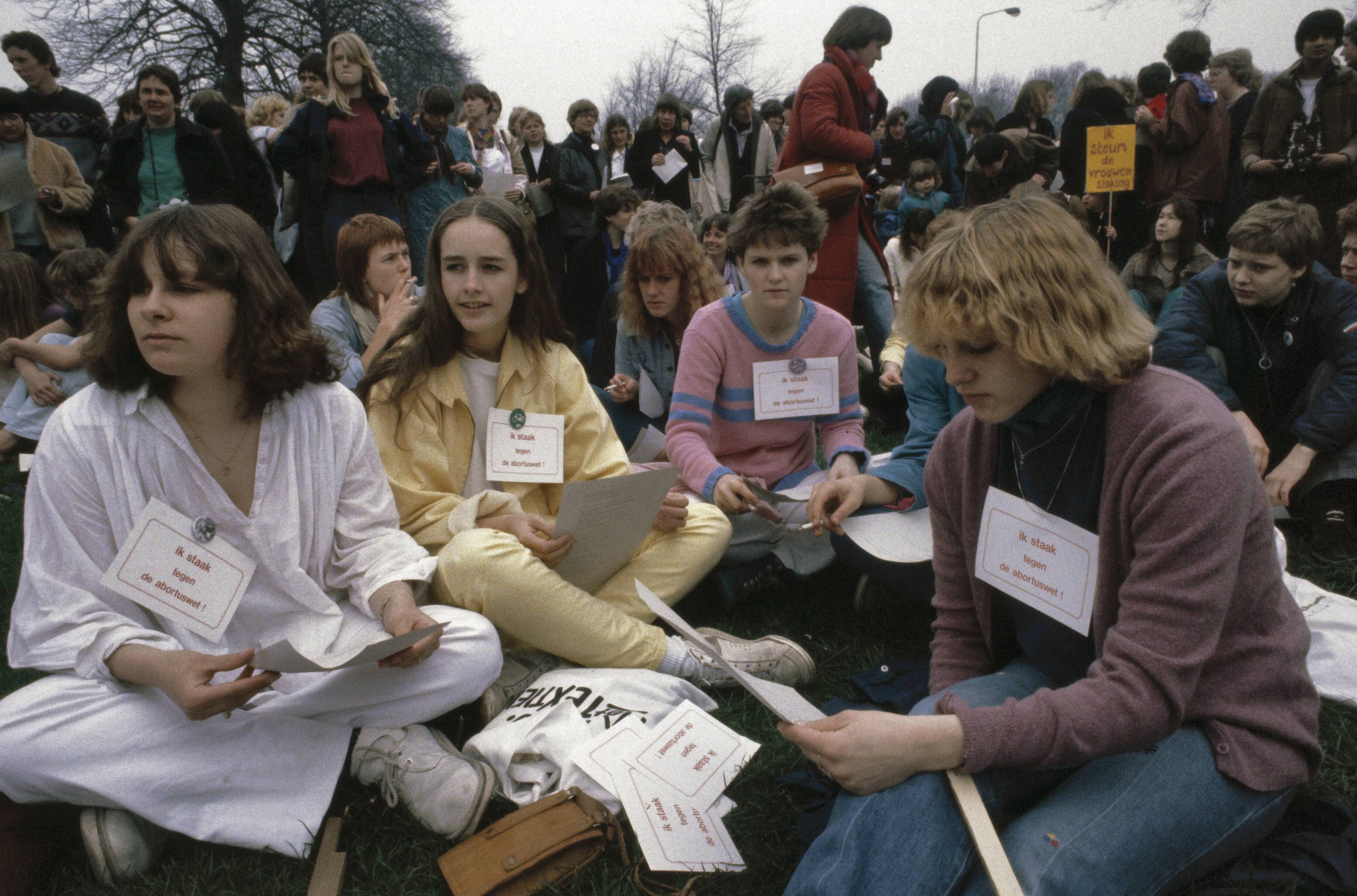 Fotocollectie Anefo — Landelijke vrouwenstakingsdag ( Den Haag ); nr. 6a , 7a: demonstrerende vrouwen met bordjes zittend op de grond in Den Haag — Foto: Dijk, Hans van / Anefo. Licentie: Set B: Rechtenvrij / Publiek Domein. Bron: Nationaal Archief. http://hdl.handle.net/10648/ad8a5fba-d0b4-102d-bcf8-003048976d84