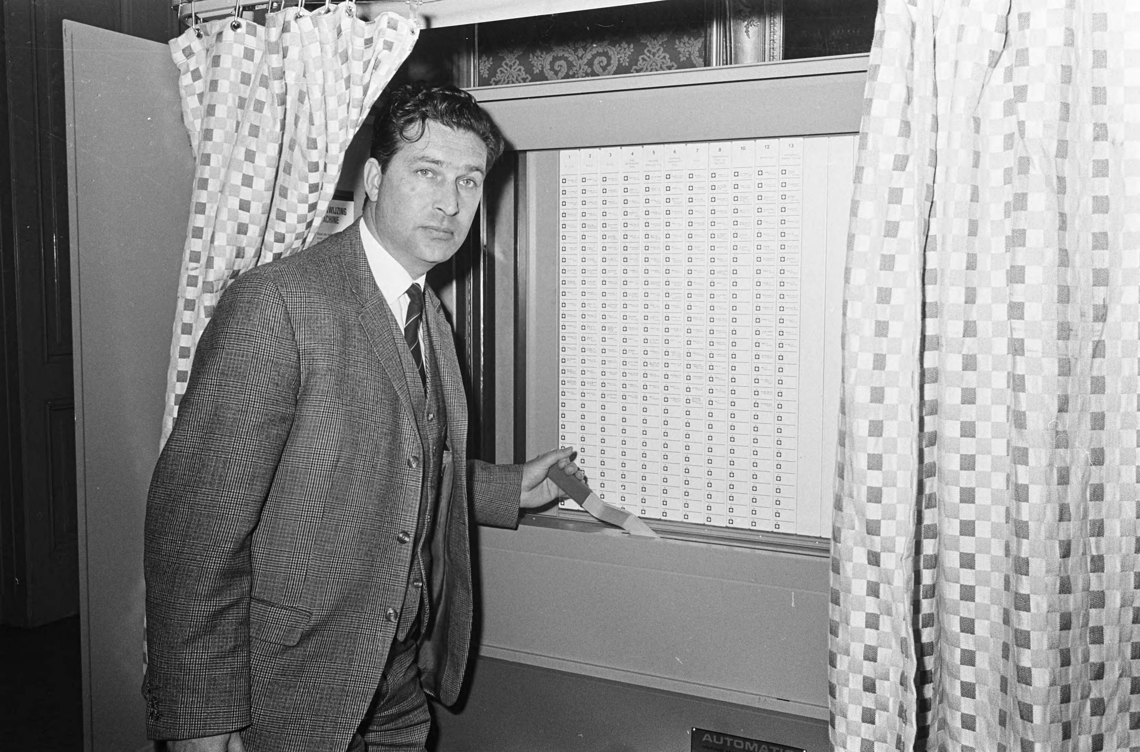 Fotocollectie Anefo — Automatisch stemmen, de machine in Wassenaar in aktie — Foto: Koch, Eric / Anefo. Licentie: Set B: Rechtenvrij / Publiek Domein. Bron: Nationaal Archief. http://hdl.handle.net/10648/aae19256-d0b4-102d-bcf8-003048976d84