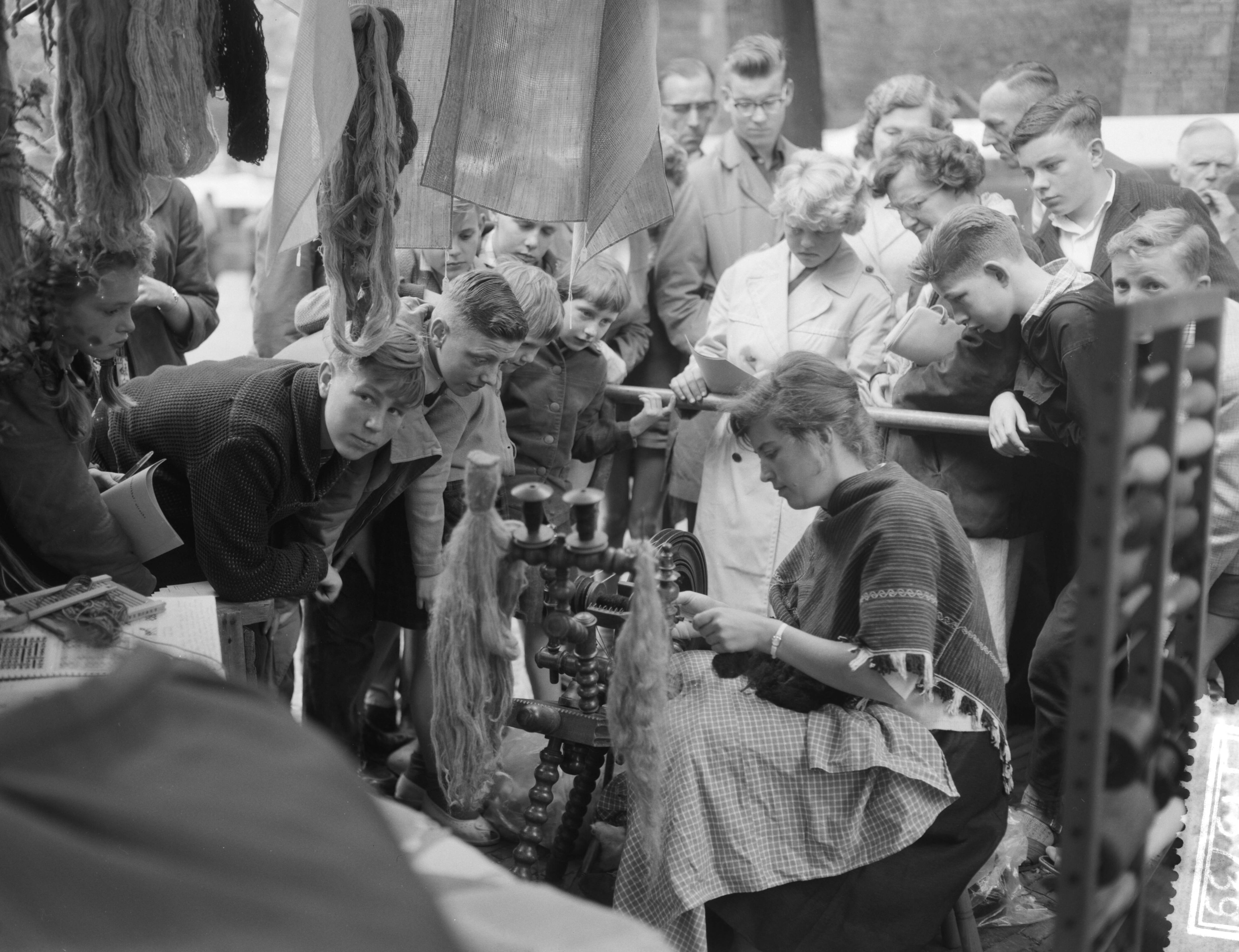 Fotocollectie Anefo — Kunstenaarsmanifestatie op het Janskerkhof te Utrecht. Kunstnaaldwerkster Helma Smit achter het spinnewiel — Foto: Bilsen, Joop van / Anefo. Licentie: Set B: Rechtenvrij / Publiek Domein. Bron: Nationaal Archief. http://hdl.handle.net/10648/a9b8cc46-d0b4-102d-bcf8-003048976d84