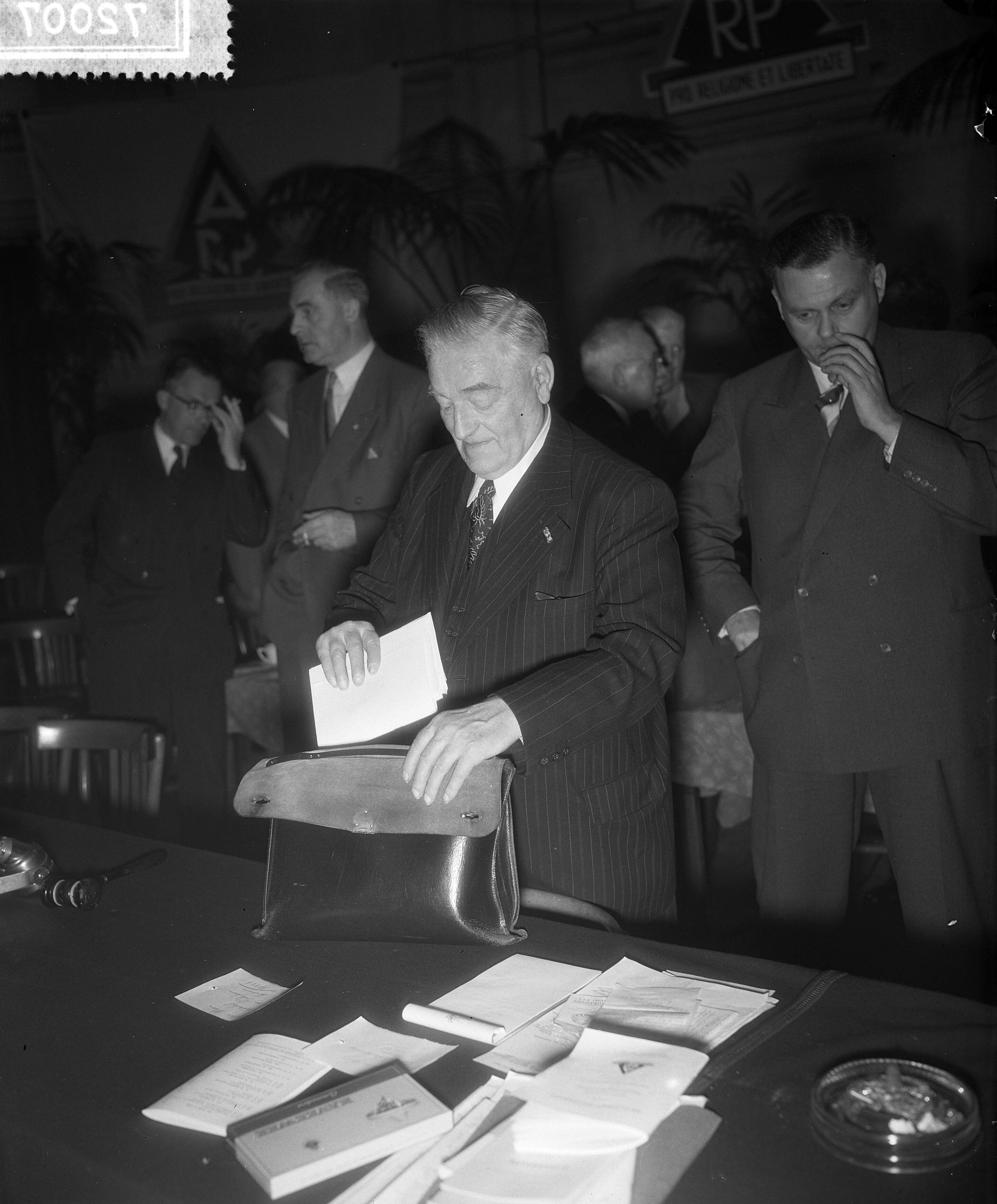 Fotocollectie Anefo — Op de deputatenvergadering van de A.R. -partij te Utrecht is wegens het aftreden van voorzitter Jan Schouten als tijdelijke voorzitter mr. A.B. Roosjen gekozen. De heer Schouten pakt zijn tas in, achter hem J. Smallenbroek — Foto: Rossem, Wim van / Anefo. Licentie: Set B: Rechtenvrij / Publiek Domein. Bron: Nationaal Archief. http://hdl.handle.net/10648/a9372fc4-d0b4-102d-bcf8-003048976d84