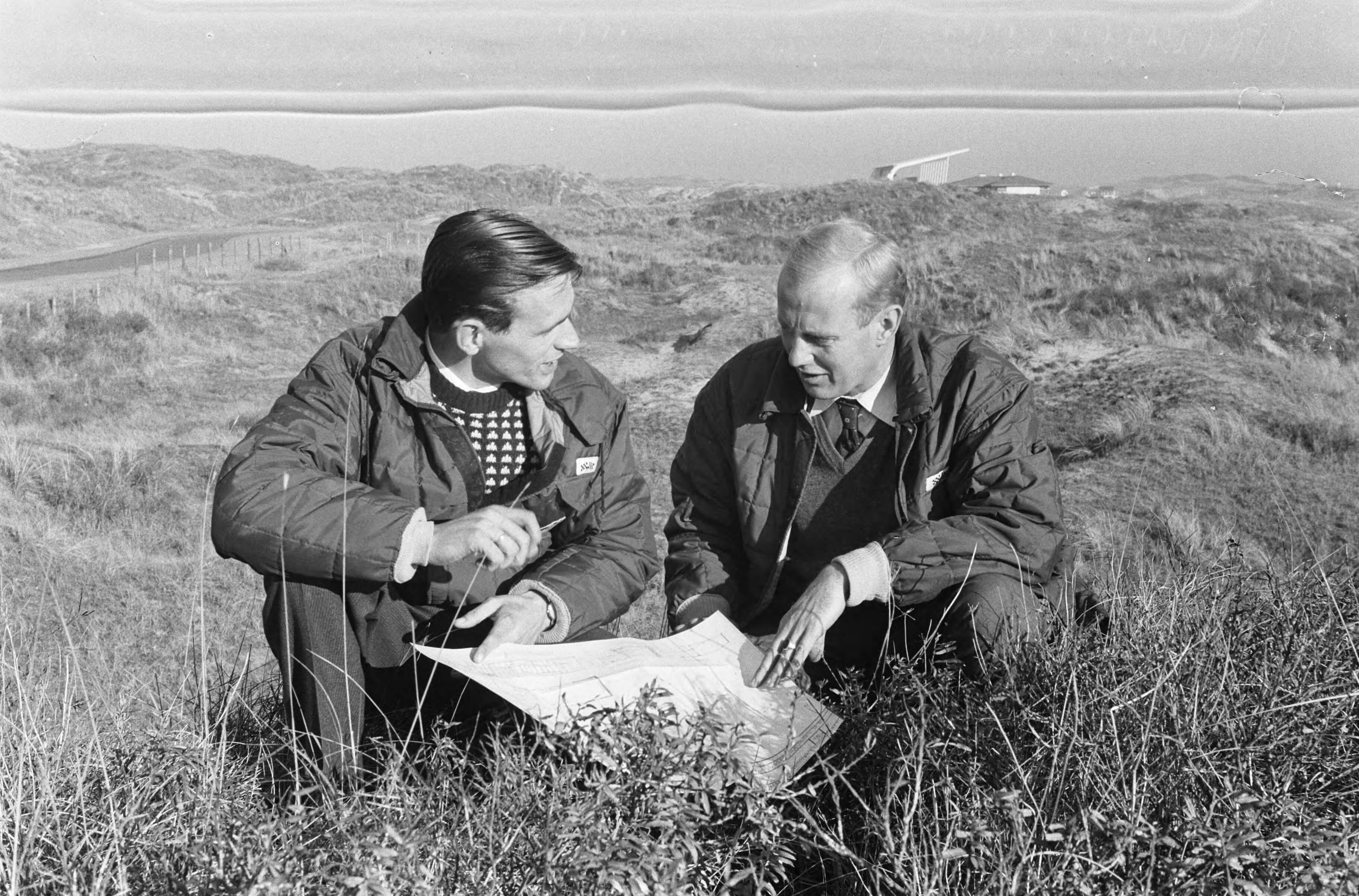 Fotocollectie Anefo — Rob Slotemaker (rechts) en Rijn Leppink, die reeds enige jaren op Zandvoort een anti-slipschool exploiteren, hopen binnen 2 jaar hun nieuwe school, bestaande uit 3 nieuwe banen van ieder 200 meter lengte voor de basisopleiding en een circuit voor de voortgezette opleiding (de enige in de wereld) te openen. Zij bekijken de tekening op het terrein, waar zij zullen gaan bouwen — Foto: Pot, Harry / Anefo. Licentie: Set B: Rechtenvrij / Publiek Domein. Bron: Nationaal Archief. http://hdl.handle.net/10648/a9ed6276-d0b4-102d-bcf8-003048976d84
